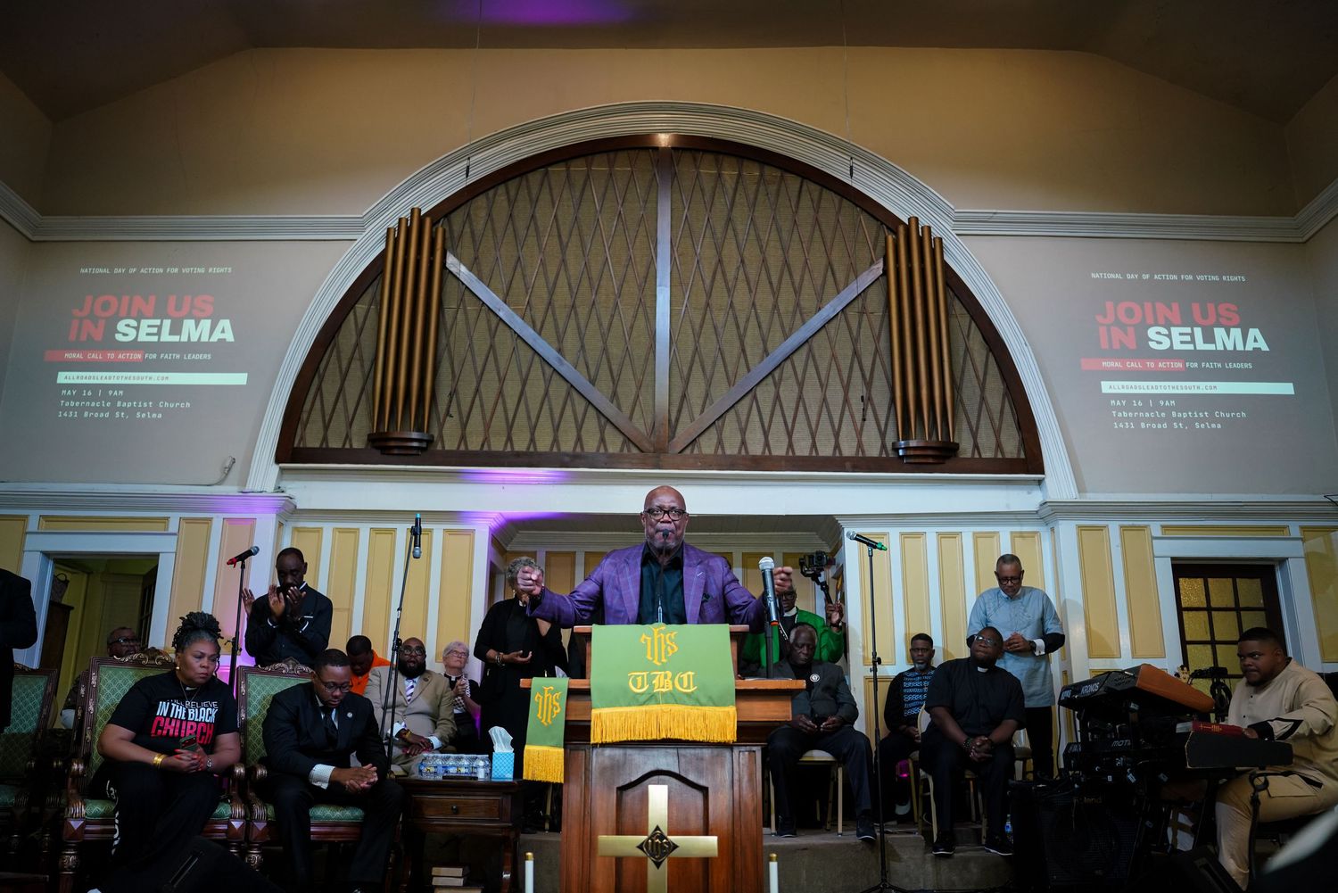 A speaker addresses a large crowd at a John Lewis in Selma commemorative church event.