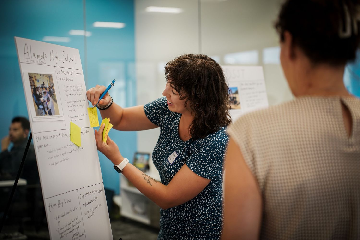 Woman writing on a large whiteboard flipchart during a collaborative workshop session.