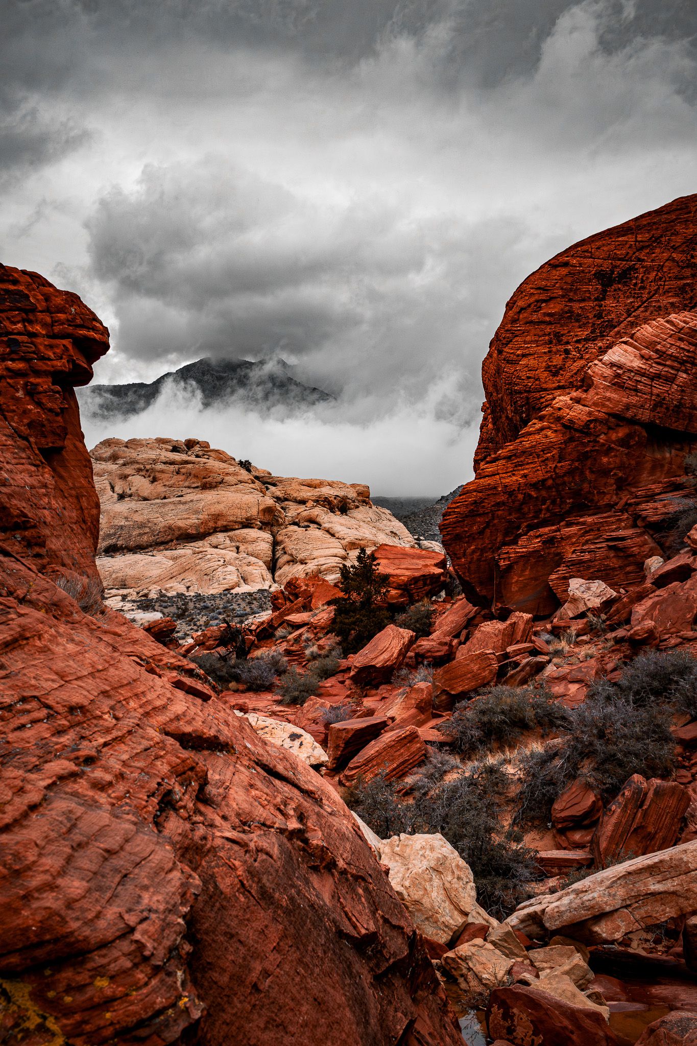 Striking red rock formations at Red Rock Canyon with dramatic storm clouds rolling over mountains.
