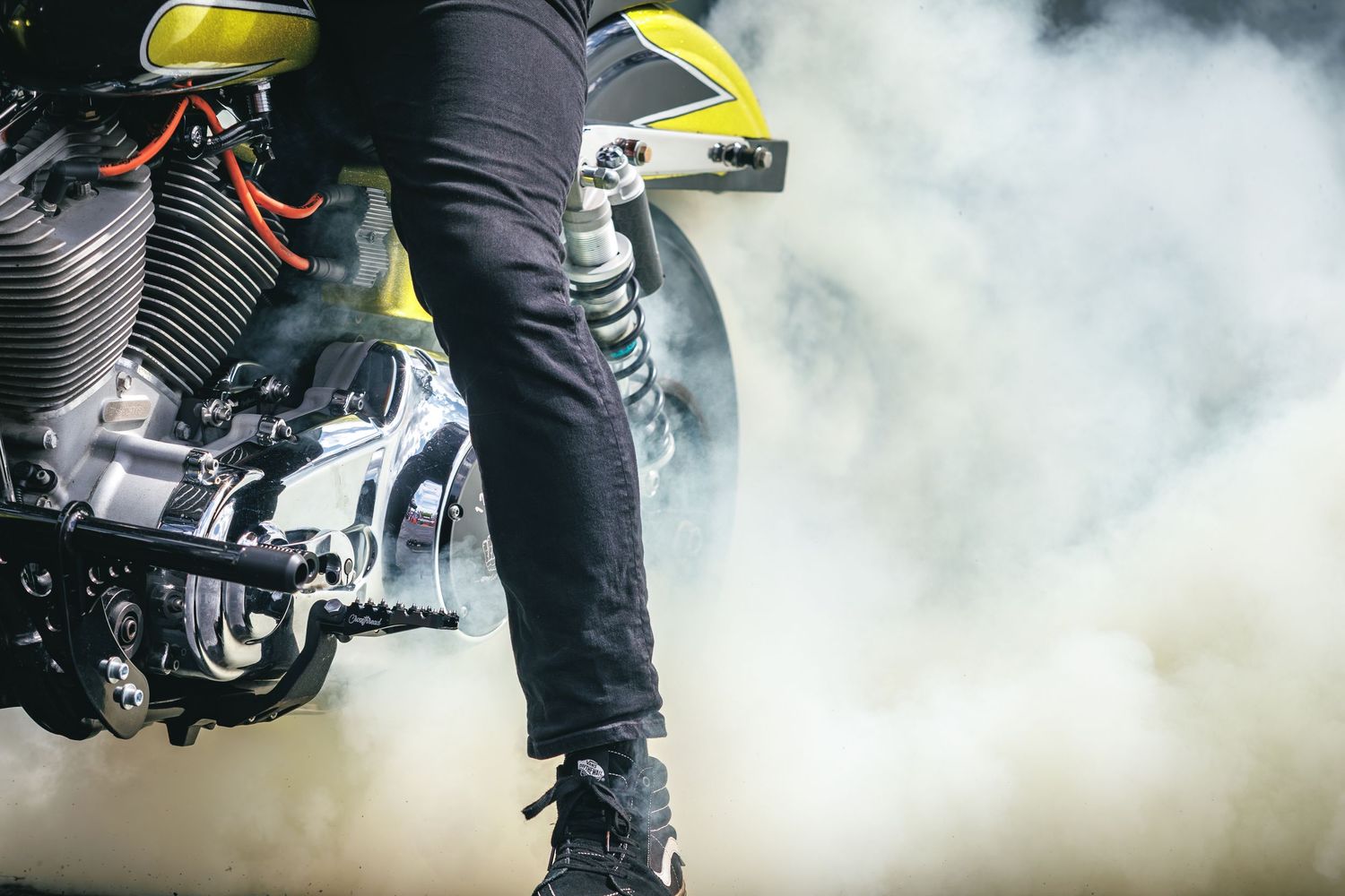 Close-up of yellow motorcycle engine with rider performing a smoky burnout.