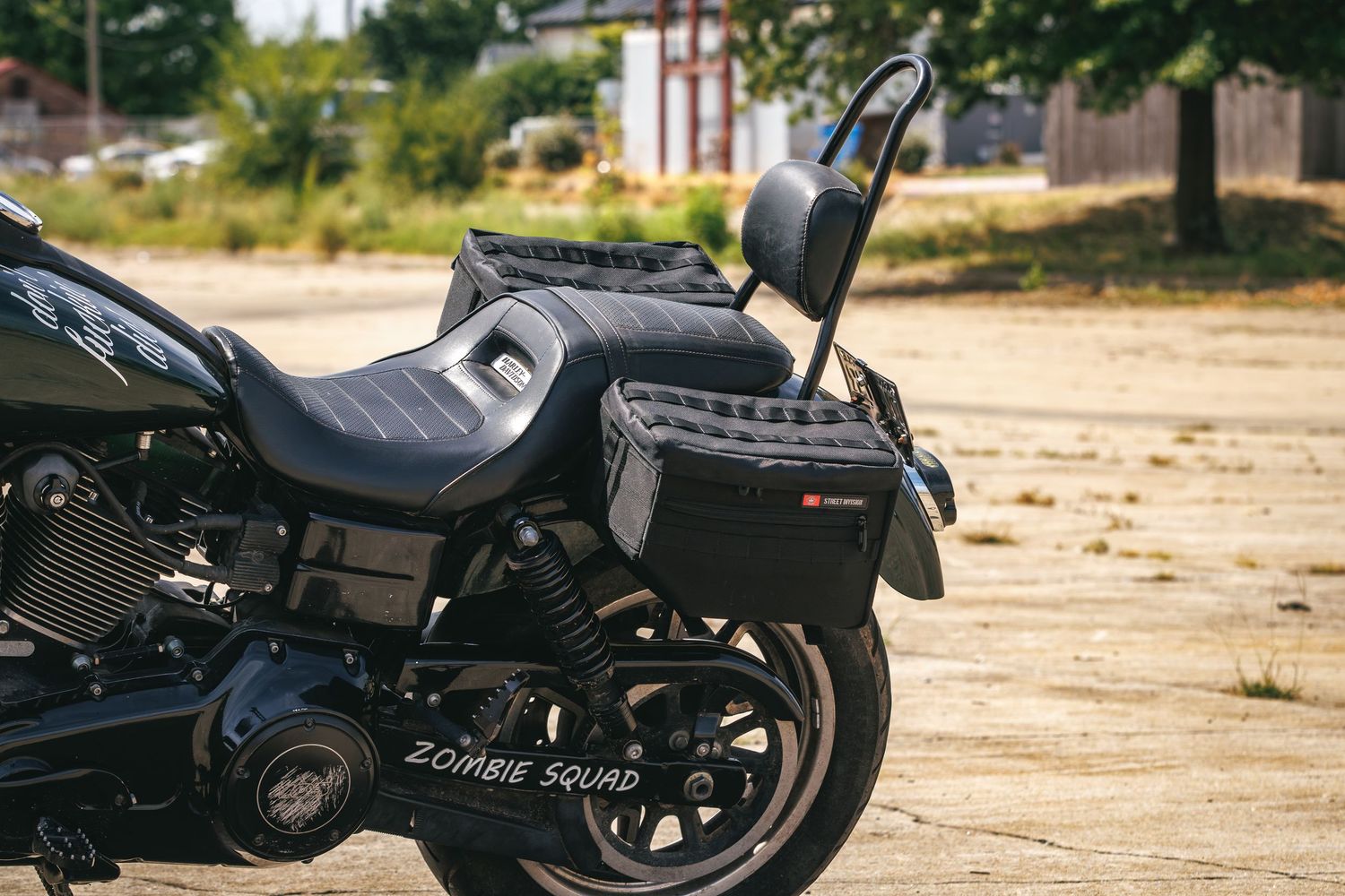 Black Harley-Davidson motorcycle with Zombie Squad decal and saddlebags parked on pavement outdoors.