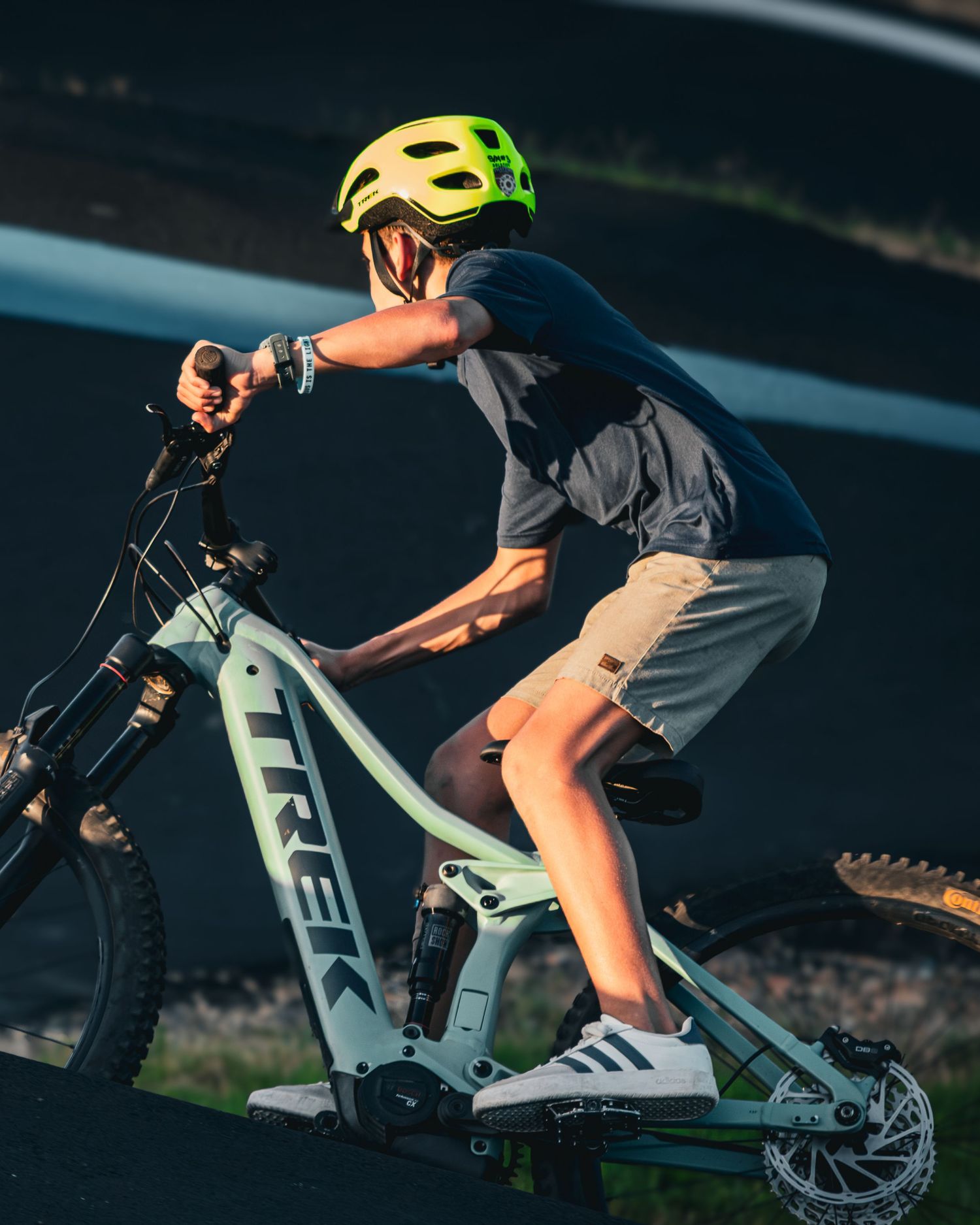 Young rider on a Trek e-bike wearing a yellow helmet on a pump track.