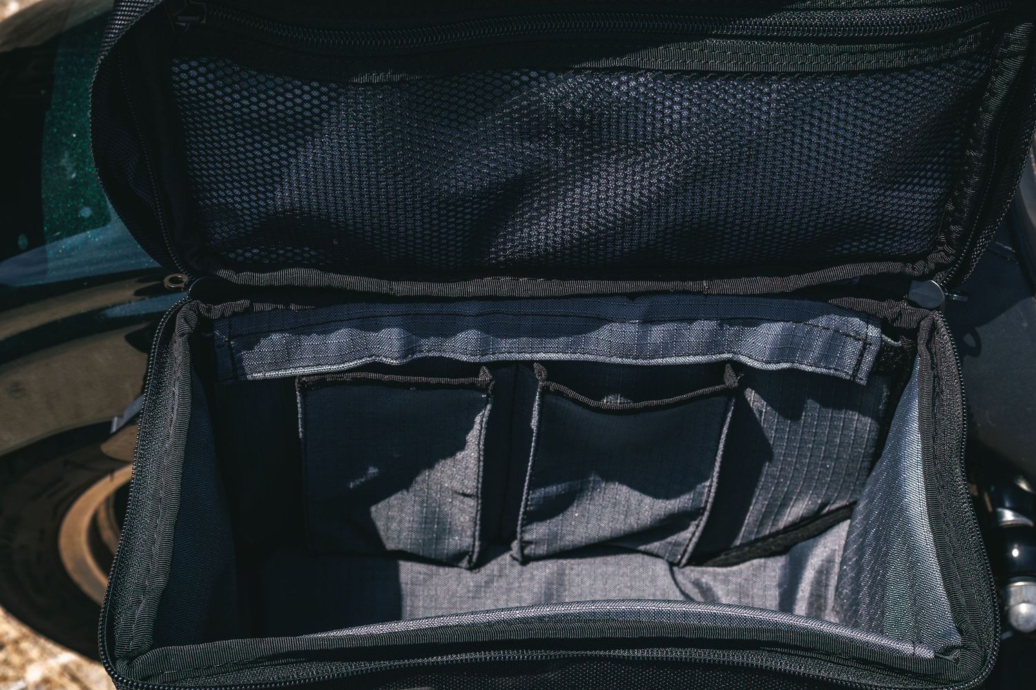 Open black camera bag with multiple padded dividers and mesh lid pocket for organized gear storage.
