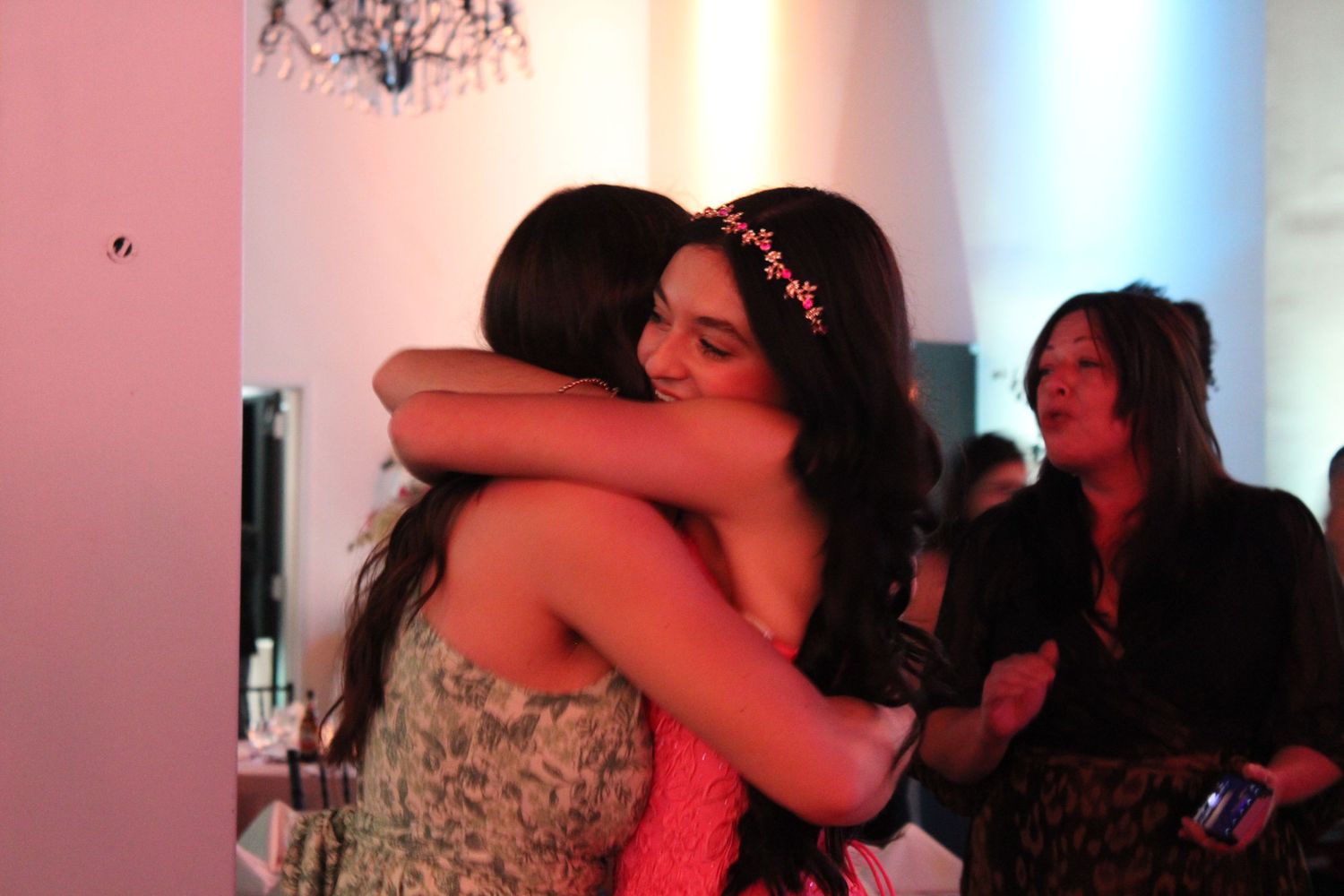 Two young women sharing a warm hug at a quinceañera party celebration.
