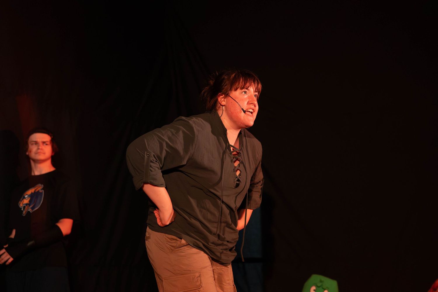 A woman laughing and leaning forward on a dark stage during a live performance.