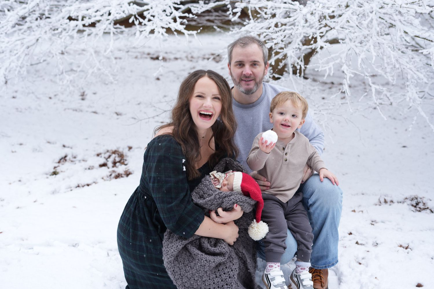 Joyful family of four laughing together in a beautiful snowy winter landscape.
