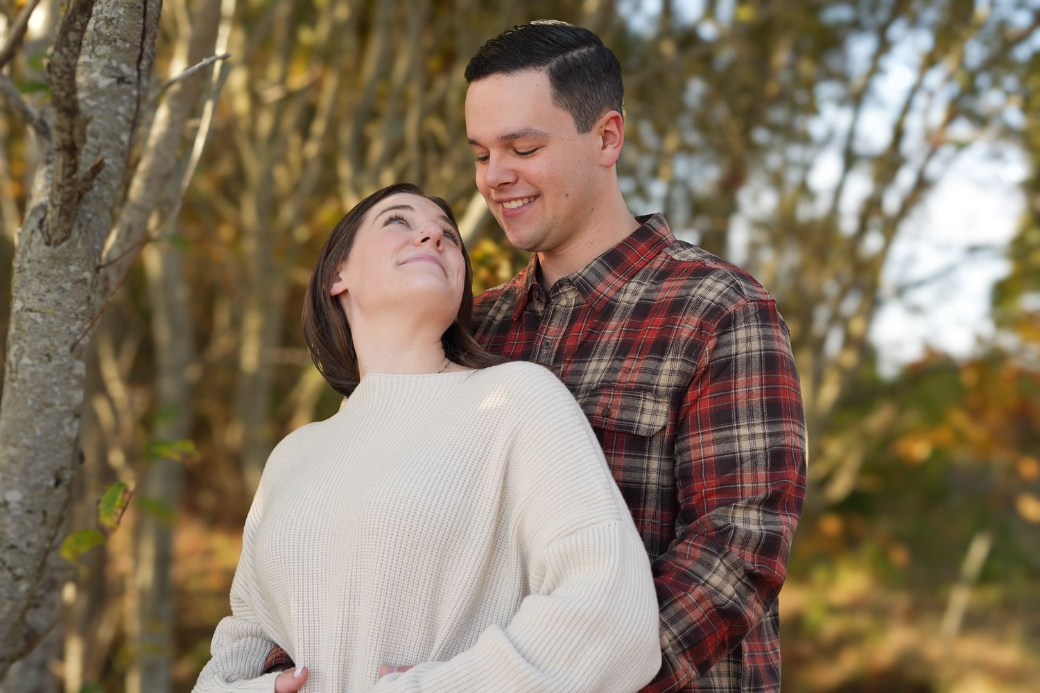 Happy couple embracing and smiling together in autumn woodland setting.