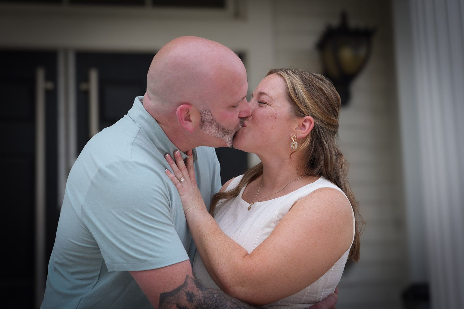 Couple sharing a romantic kiss during their wedding ceremony outdoors.