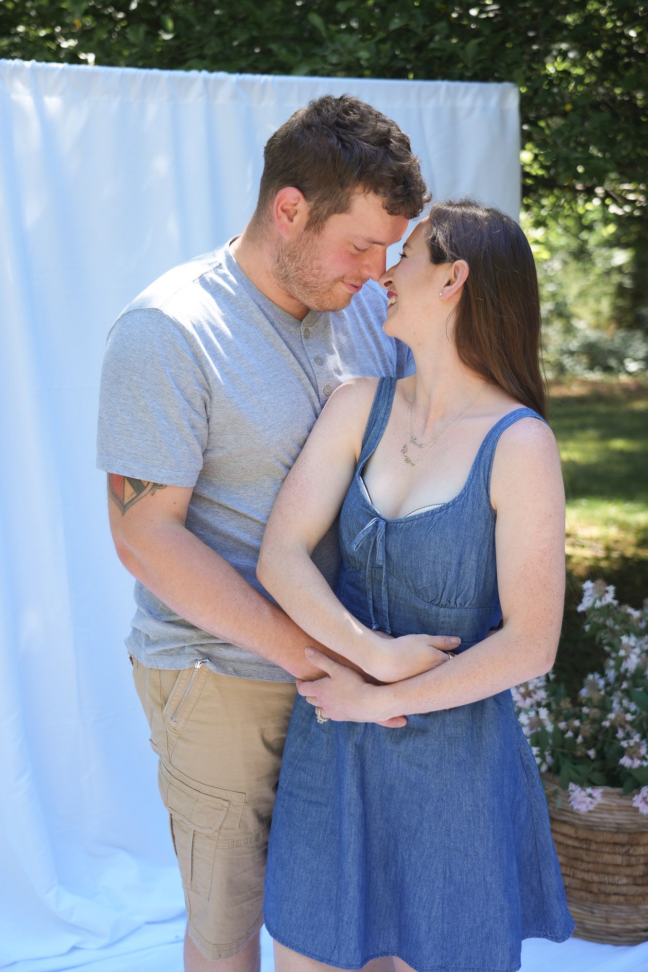 Young couple sharing a romantic moment together outdoors in front of white fabric backdrop.