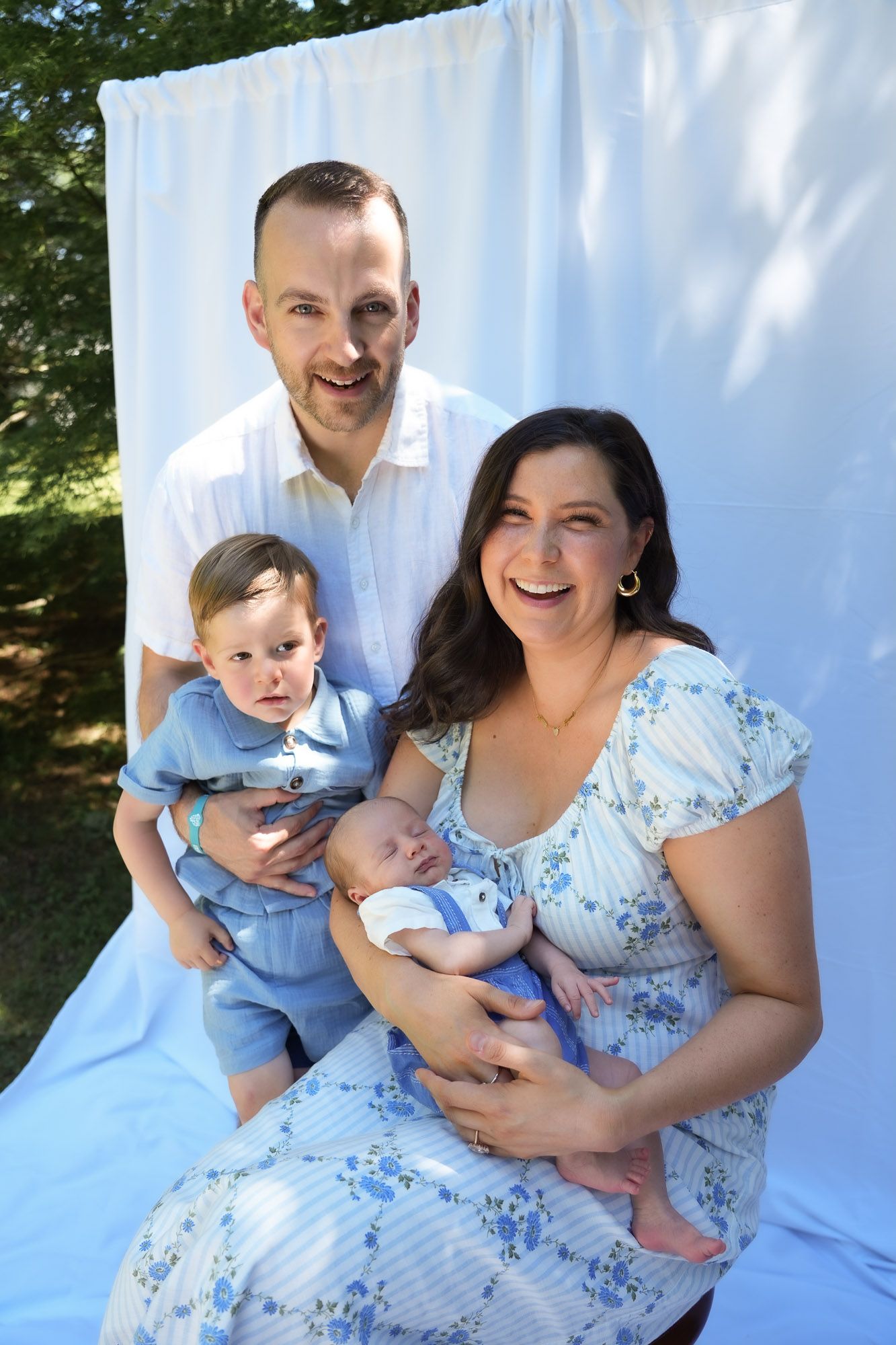 Laughing family of four with two young boys during outdoor photo session.