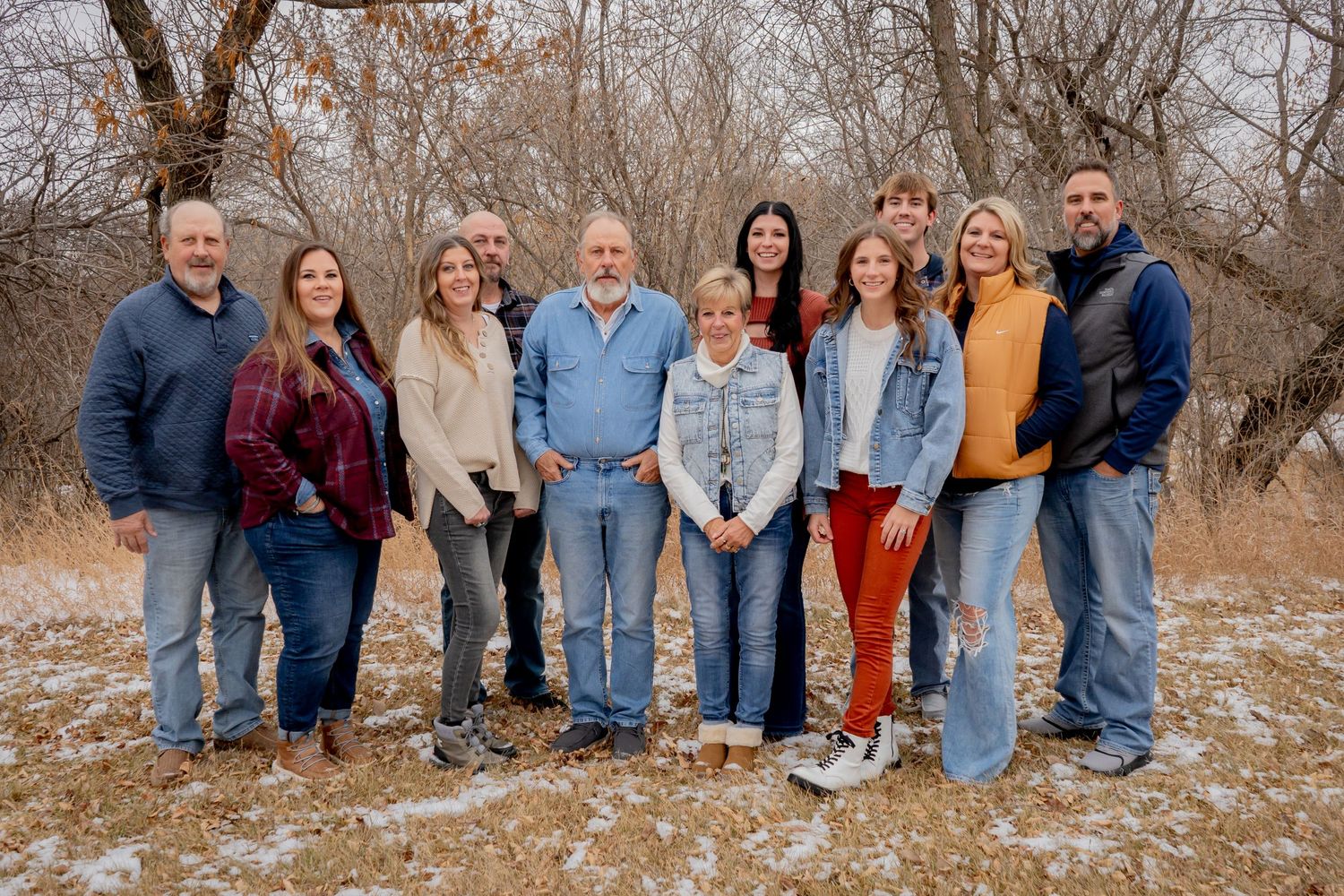 Large extended family group of ten people posing together outdoors in snowy winter landscape.