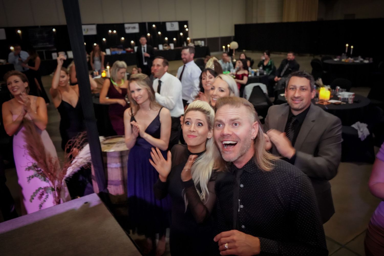 Excited crowd of guests celebrating and cheering at an elegant evening gala or awards event.