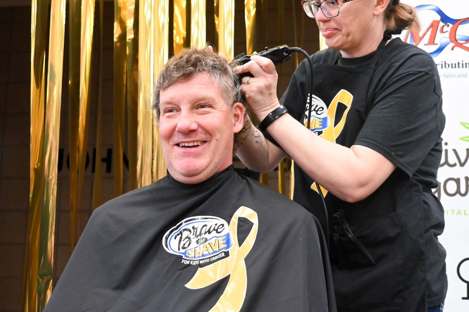 Happy man smiling while getting his head shaved at a Brave the Shave charity event.