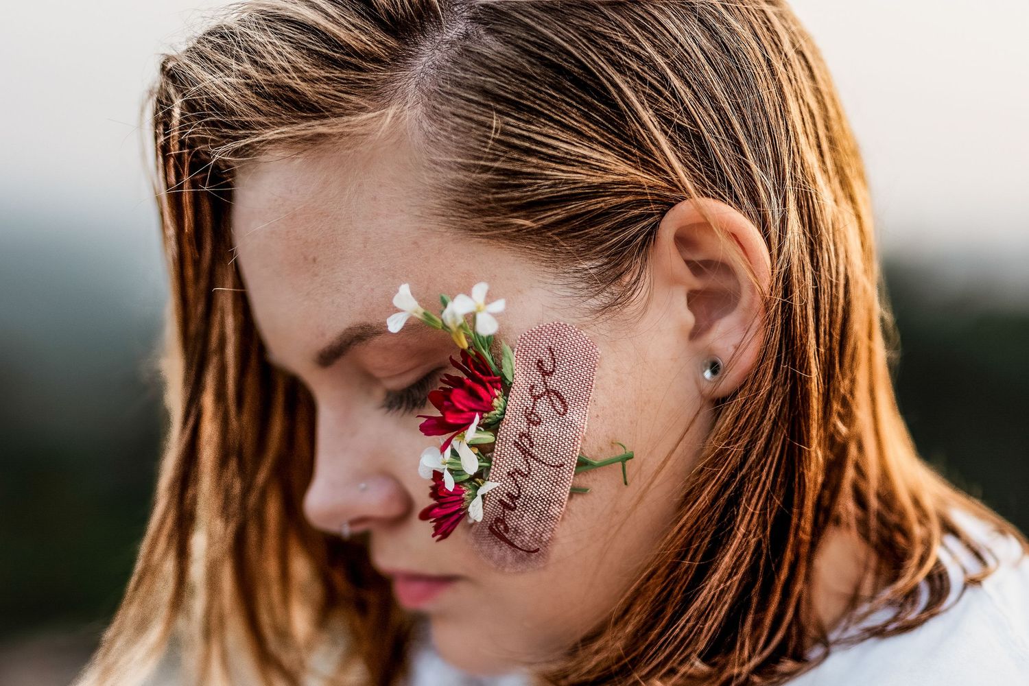 Side profile of a woman’s face with a Band-Aid labeled ‘Purpose’ and delicate flowers, symbolic self-portrait in Windsor, Ontario.