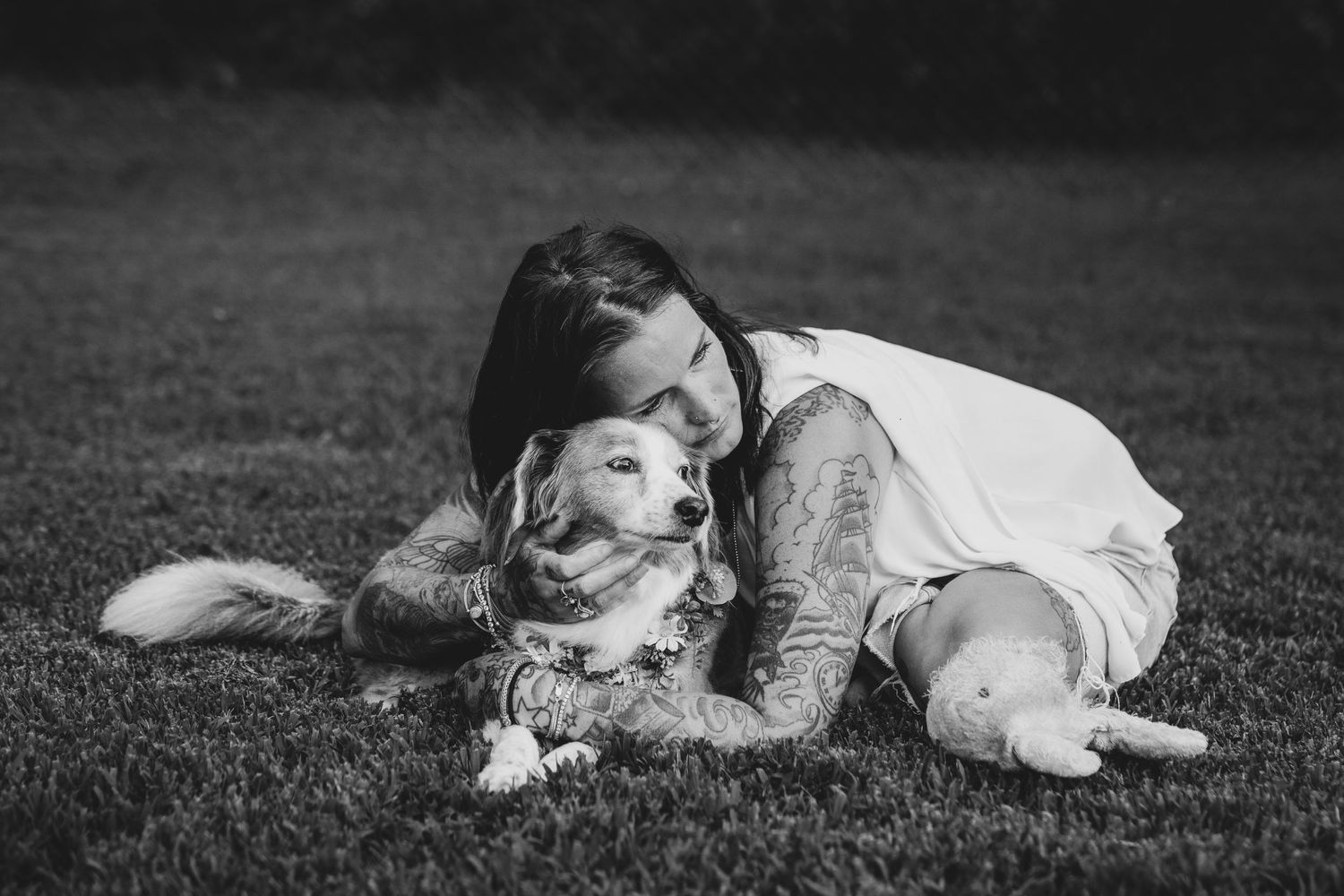 Black-and-white photo of a woman and her dog sitting in the grass during an end-of-life pet portrait session, Windsor Ontario.