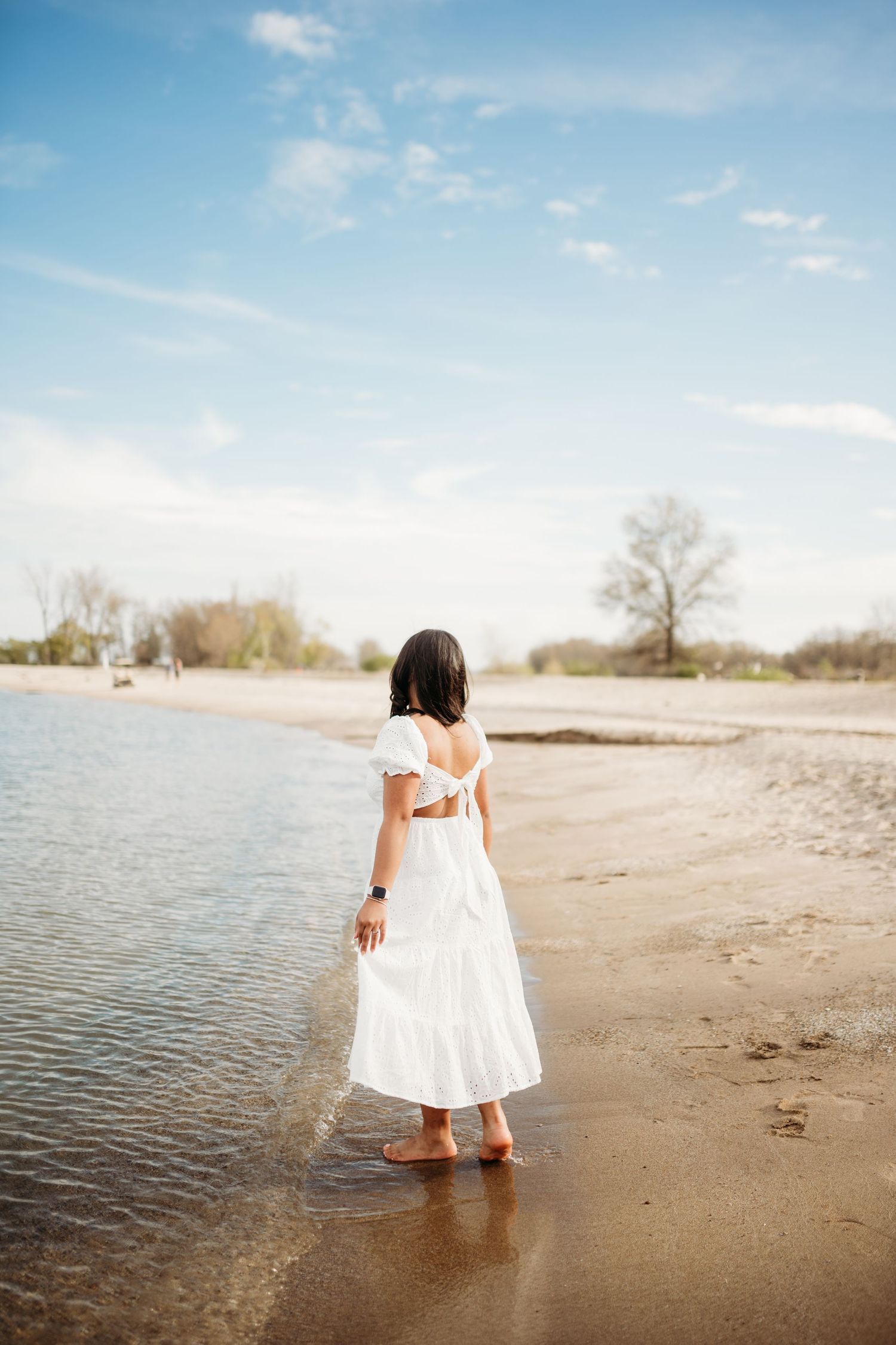 White dress reflection in shallow water at beach during sunset.