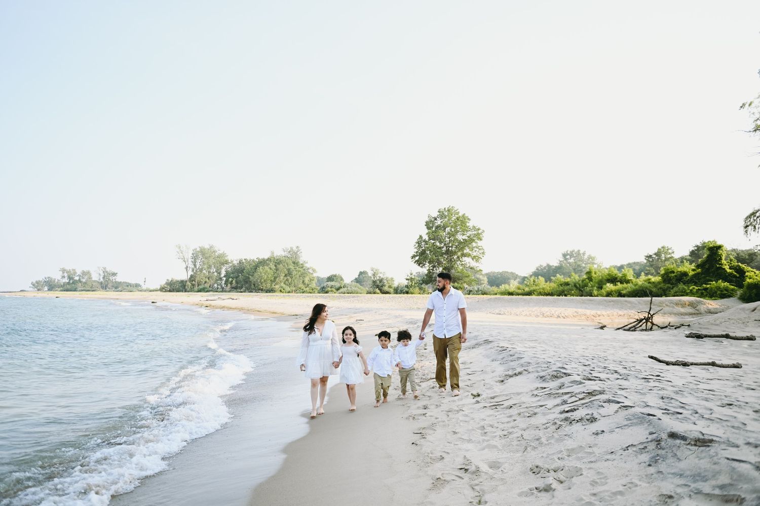 Family walking together along a serene beach shoreline at sunset.