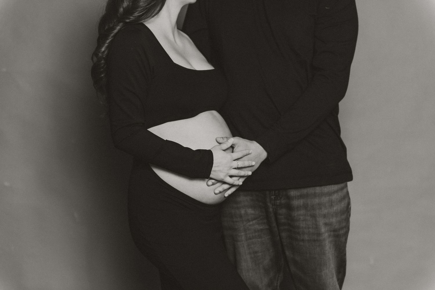 Black and white maternity photo showing a couple embracing.