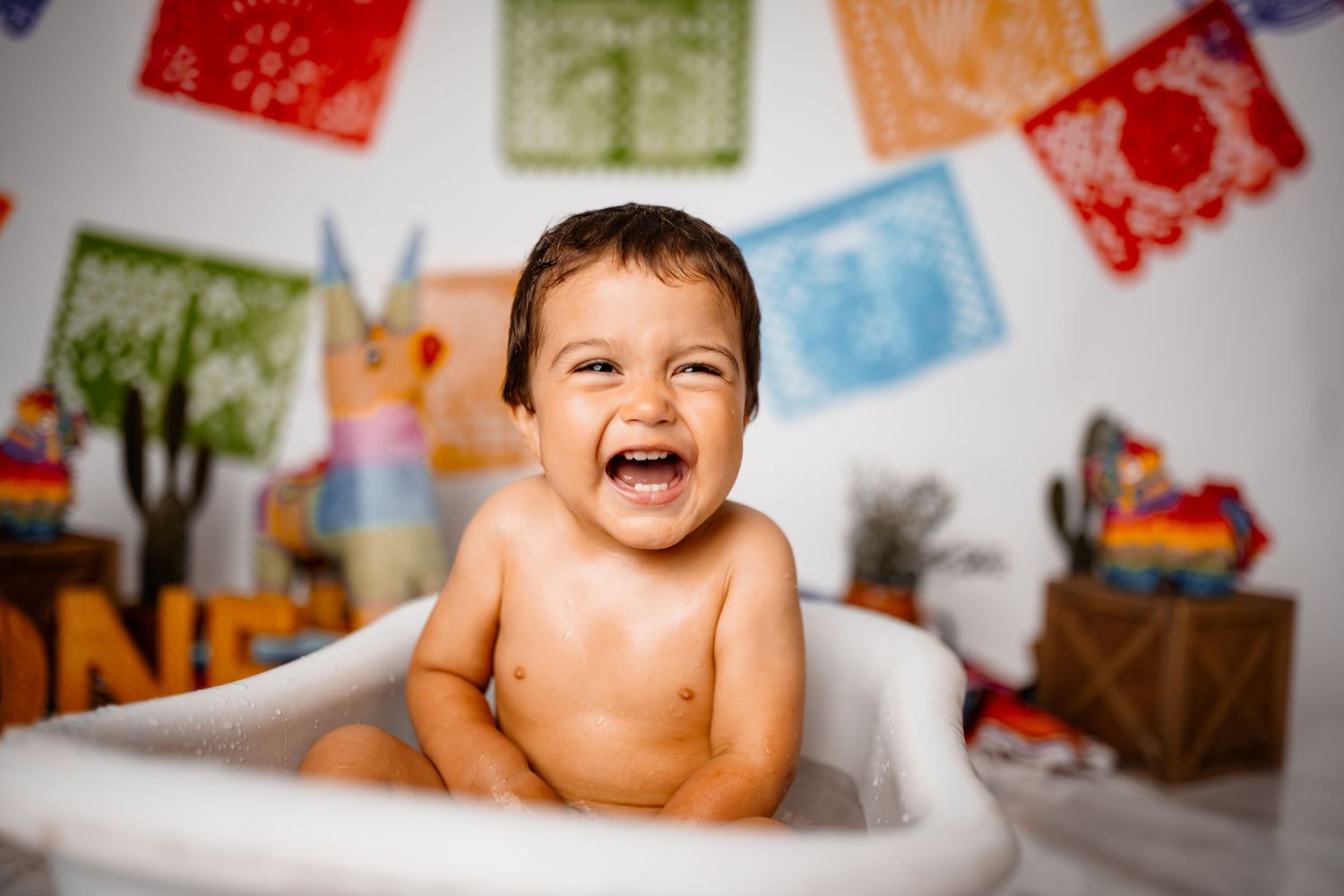 Bright papel picado banners decorate a white backdrop for a celebration setup.