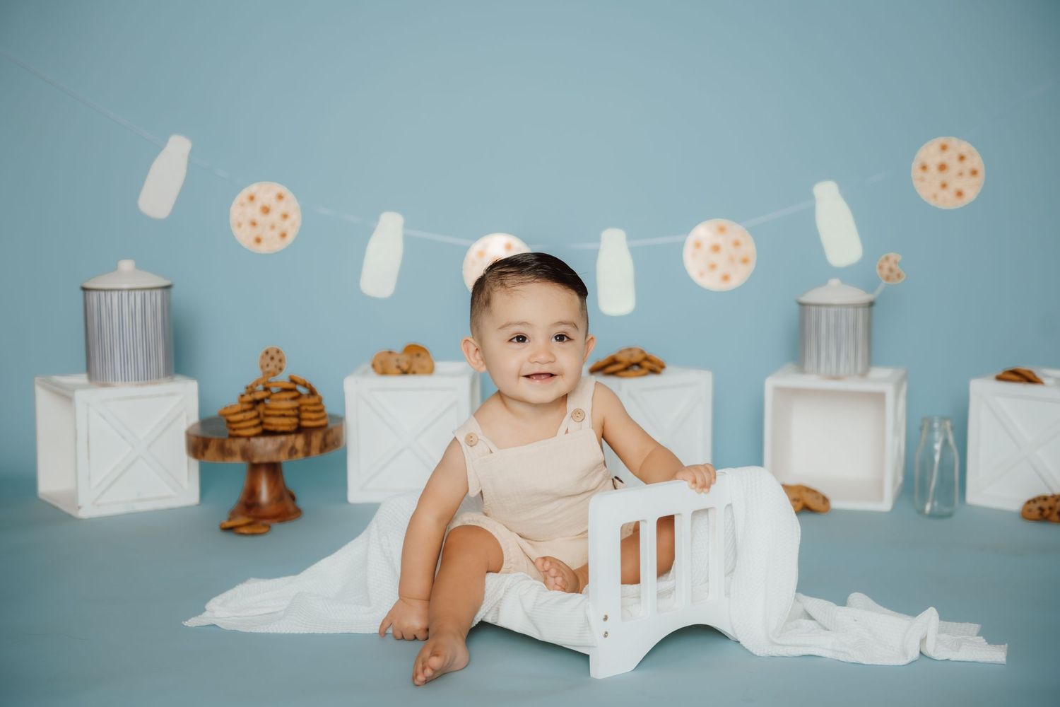 Baby milk bath photography setup with white props and cookie decorations.