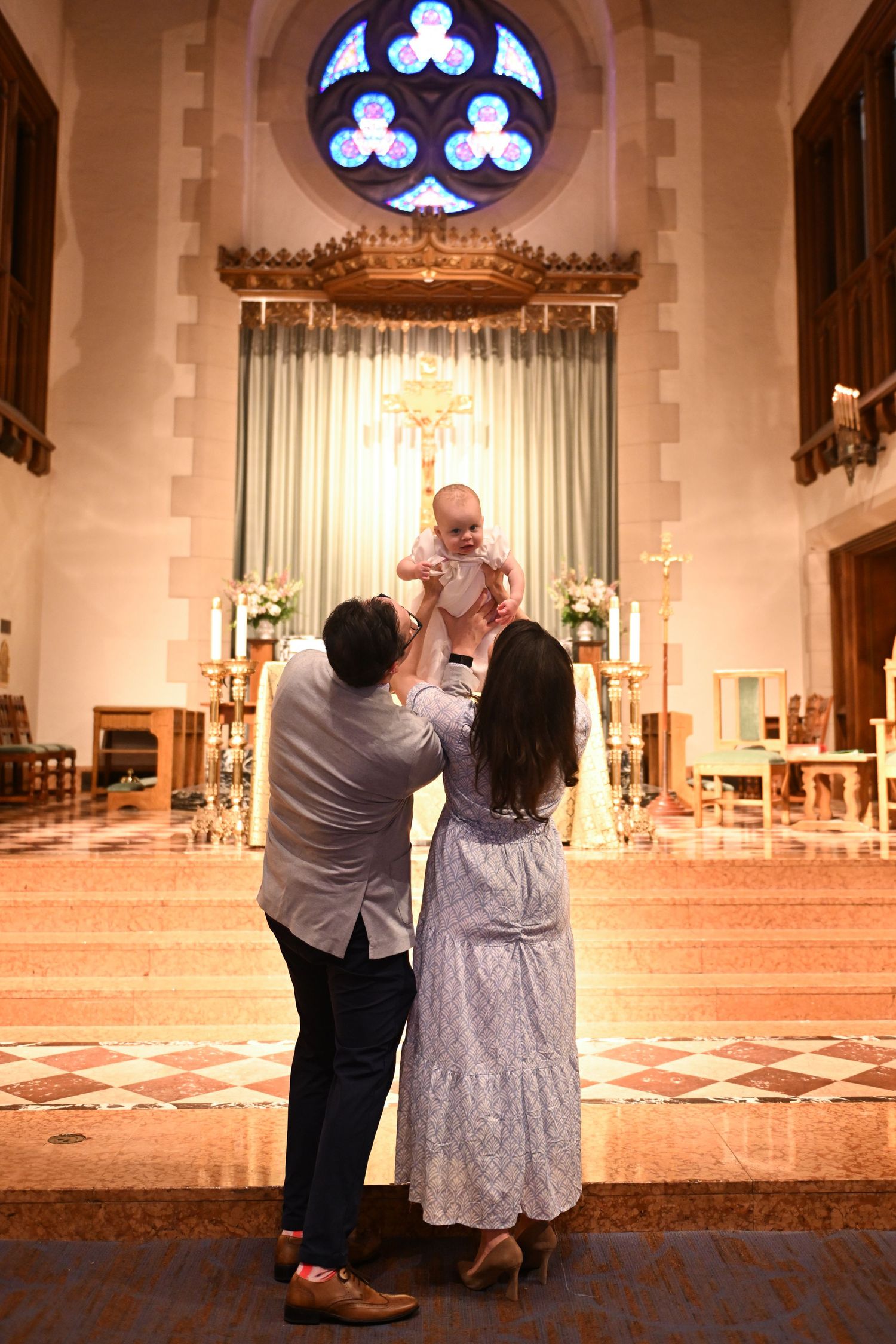 Church interior with stained glass windows and couple sharing ceremonial moment.