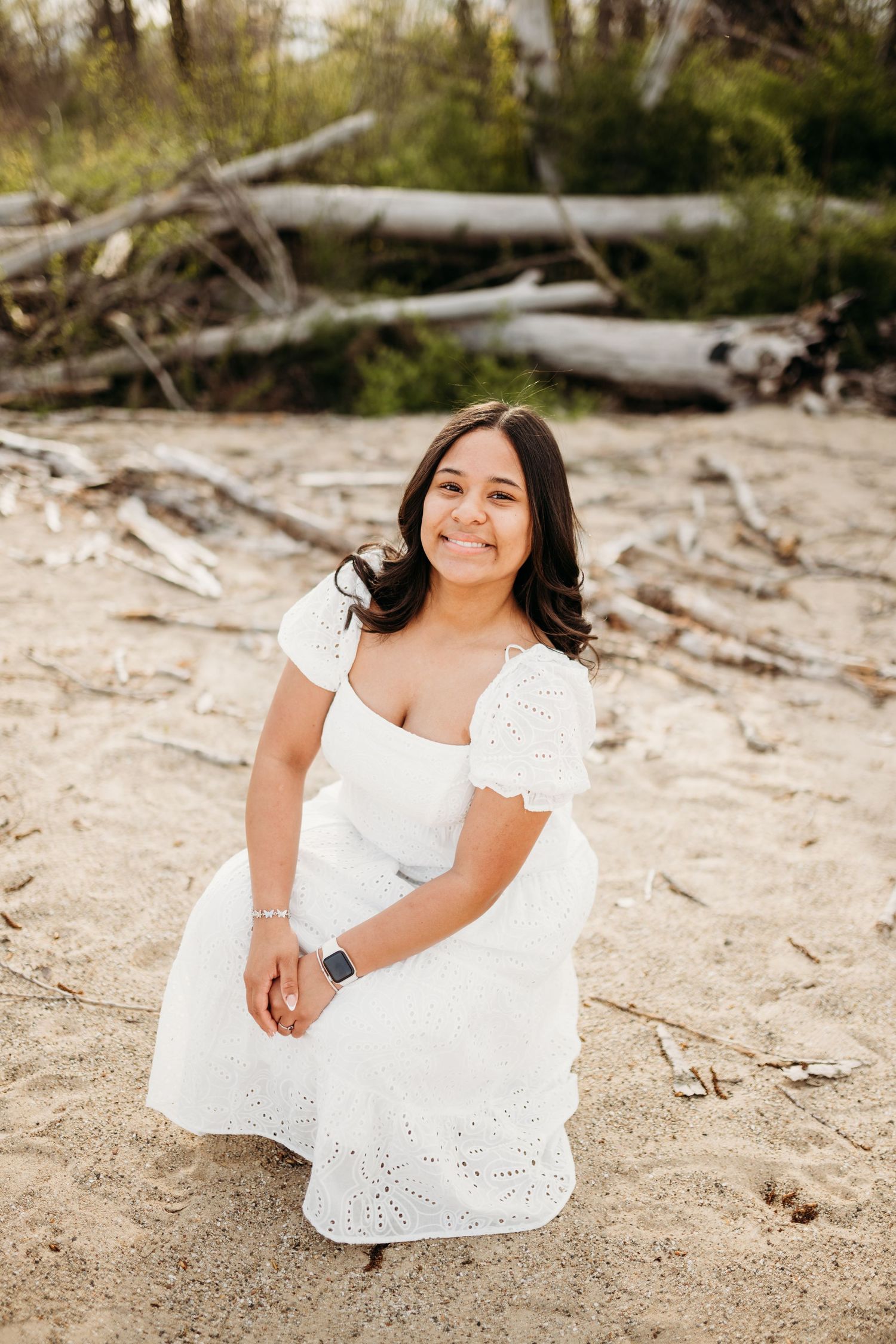 Outdoor portrait session on sandy beach with driftwood and natural lighting.