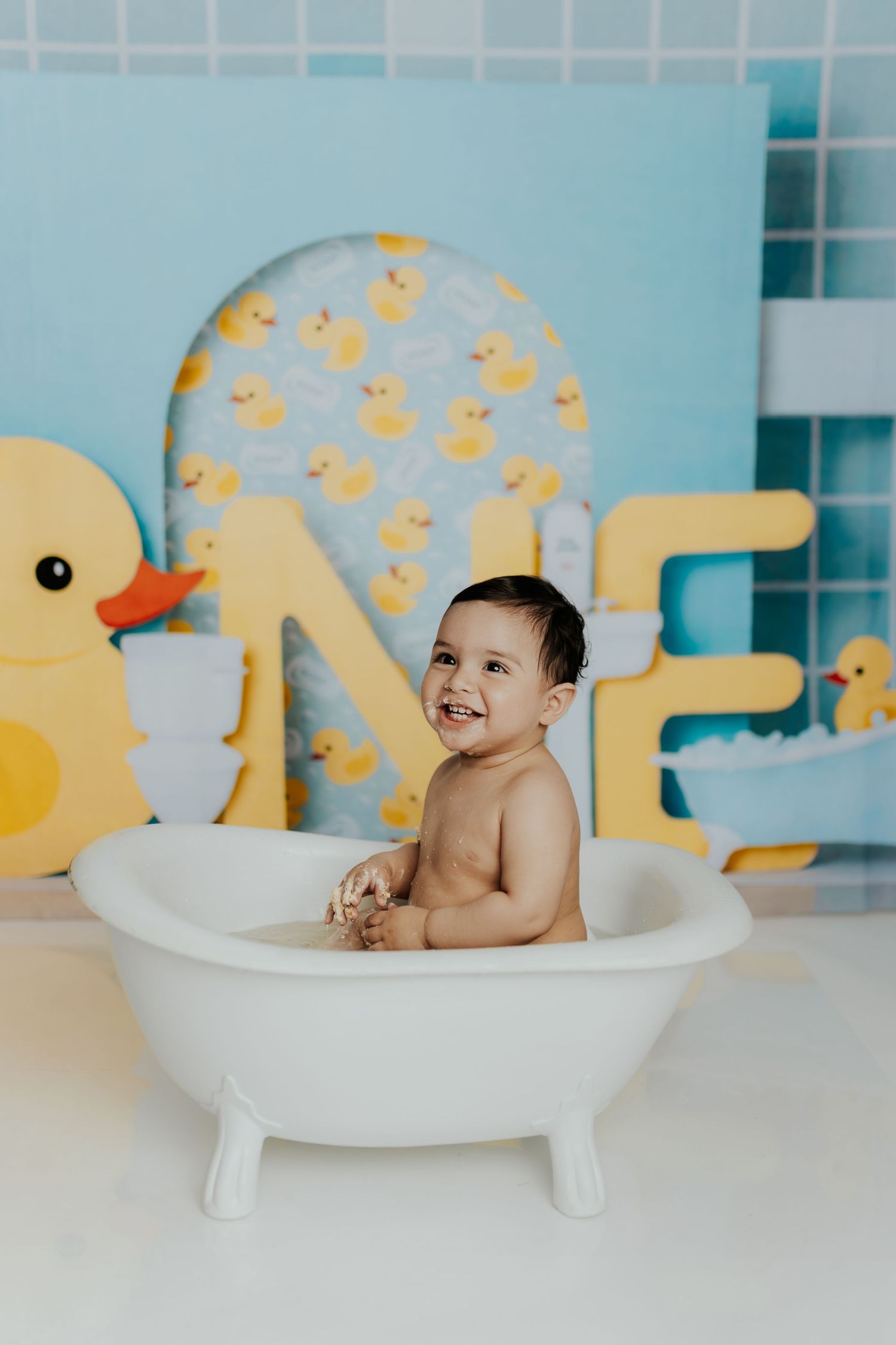 Bathtub scene with yellow rubber duck decorations and blue tile background.