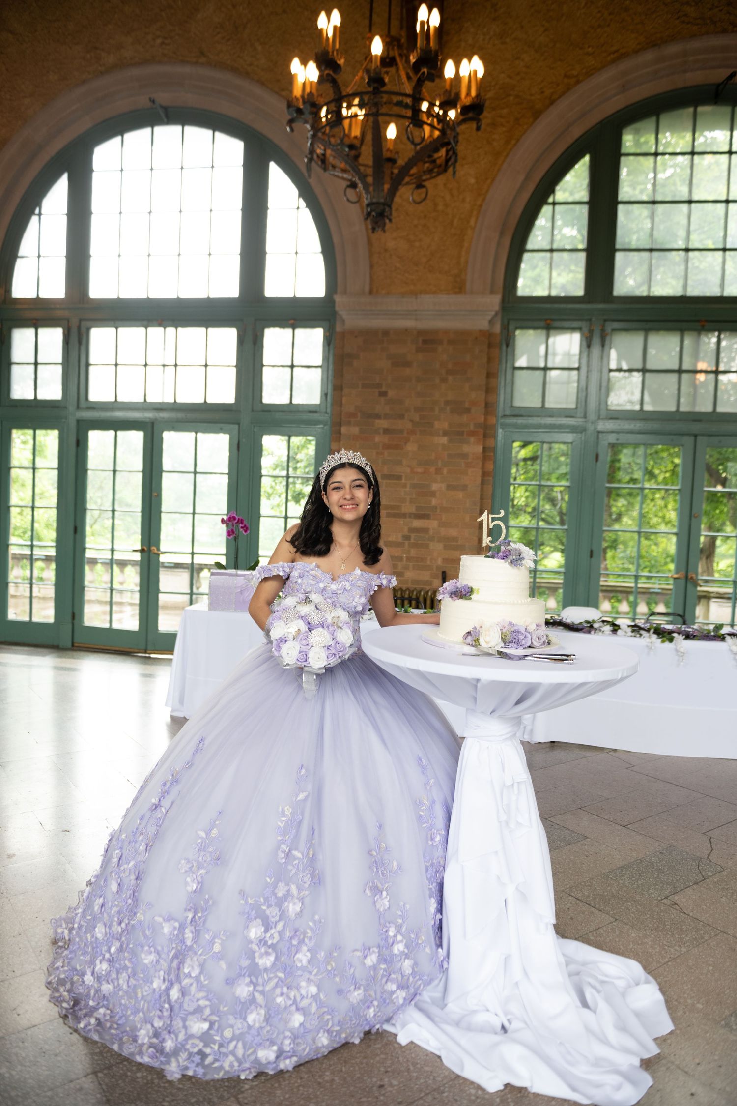 Grand ballroom with arched windows and elegant decor featuring lavender and white color scheme.