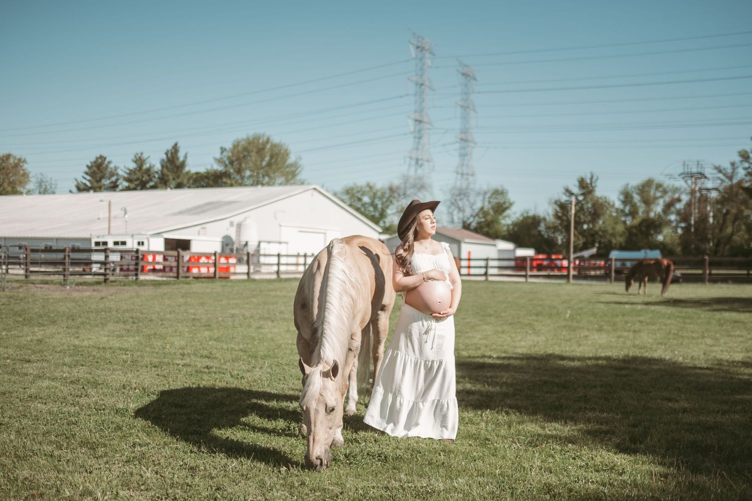 Artistic maternity photography session in an open field with power lines in background.