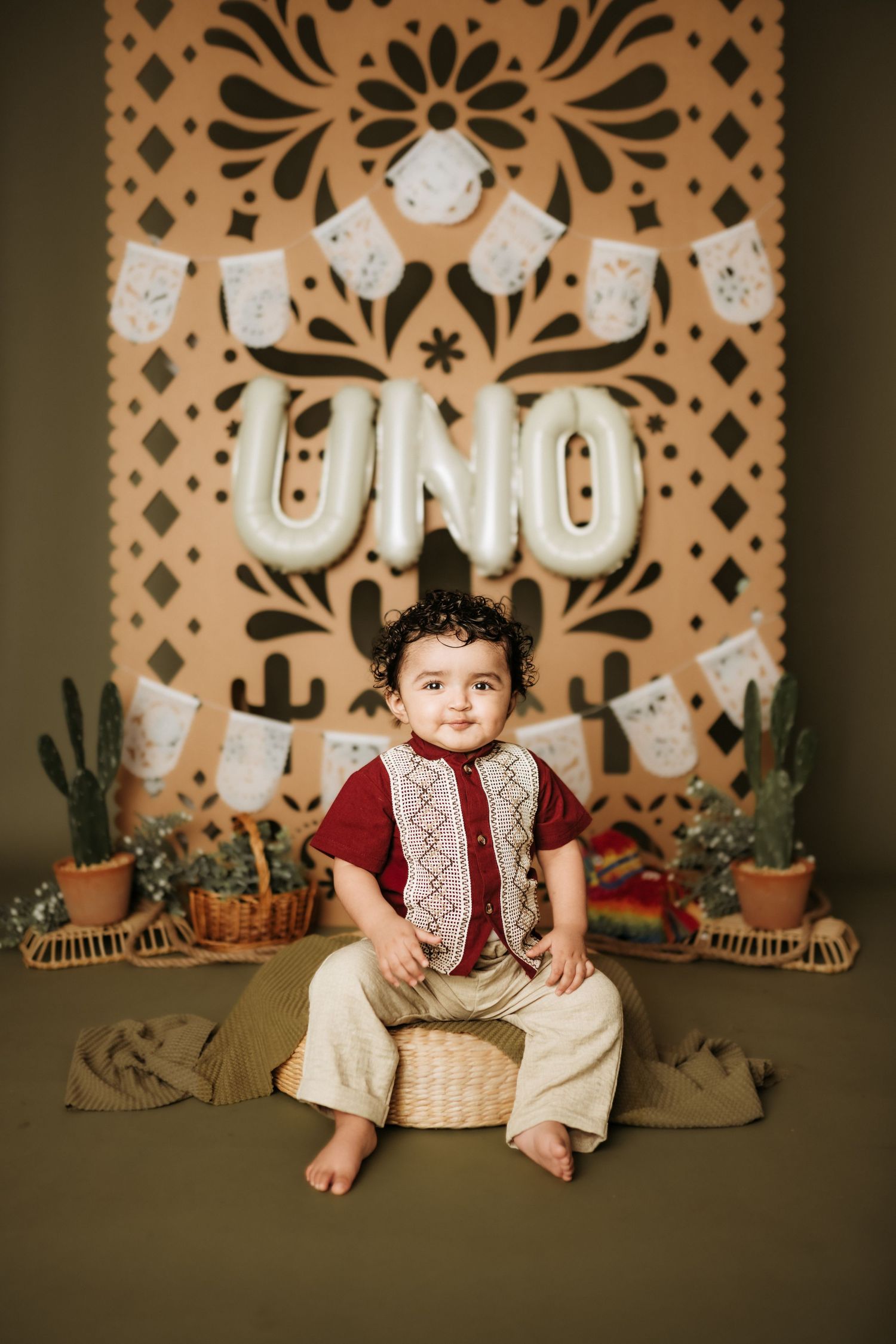 Mexican themed first birthday setup with papel picado decorations and cactus accents.