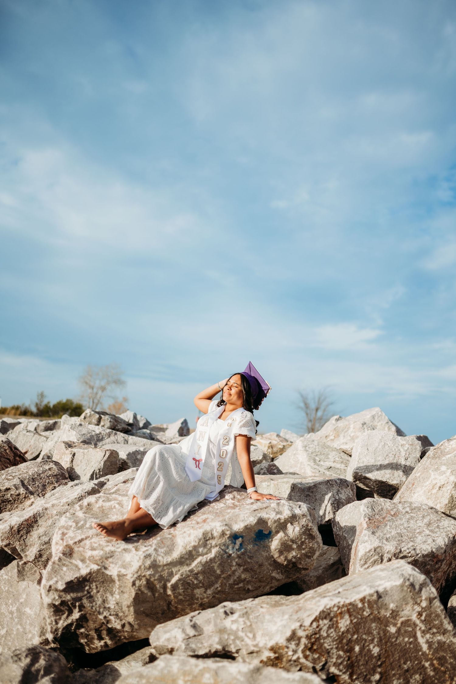Artistic poses on large coastal rocks against blue sky background.