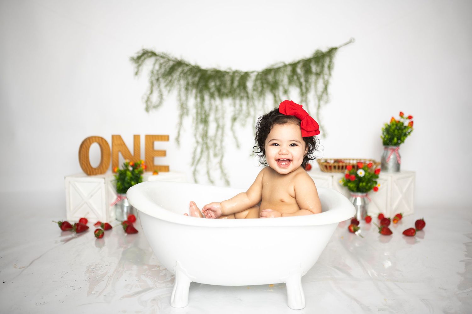 Strawberry themed first birthday setup with white chair and rustic decorations.