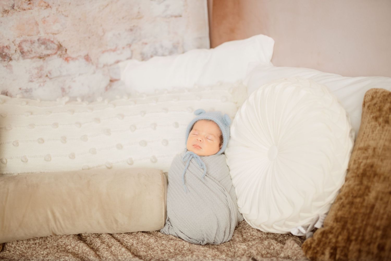 Simple newborn photography setup with white pillows and neutral tones.
