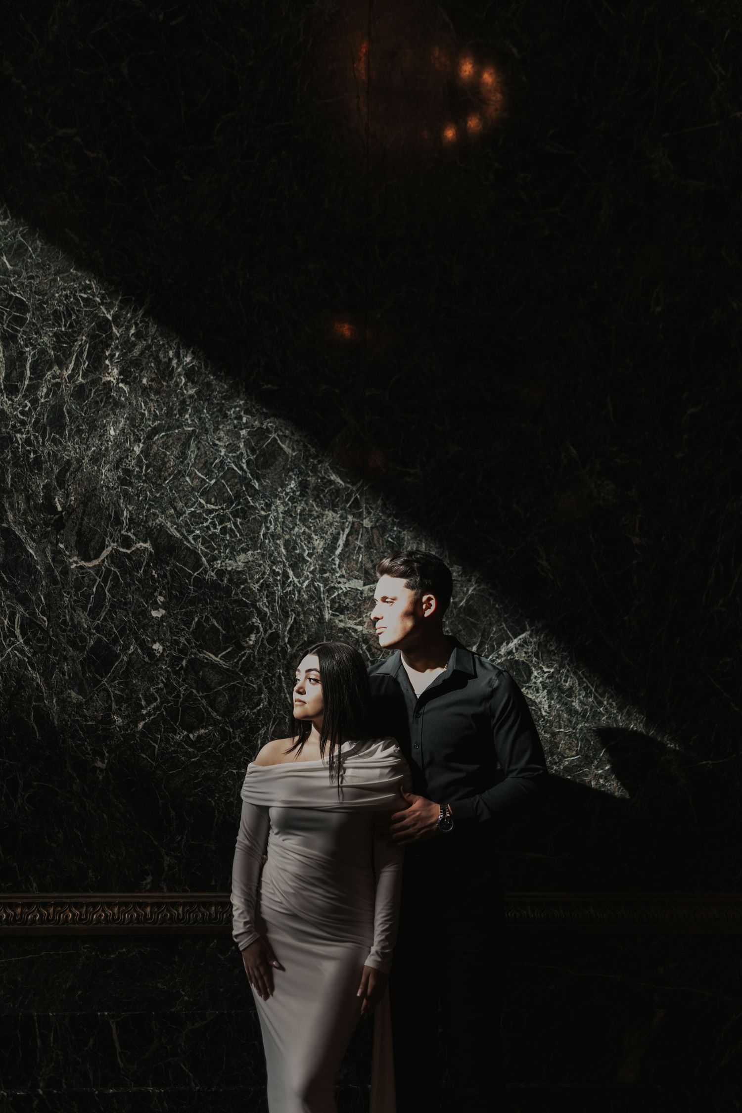Dramatic moody portrait session against dark textured background in evening light.