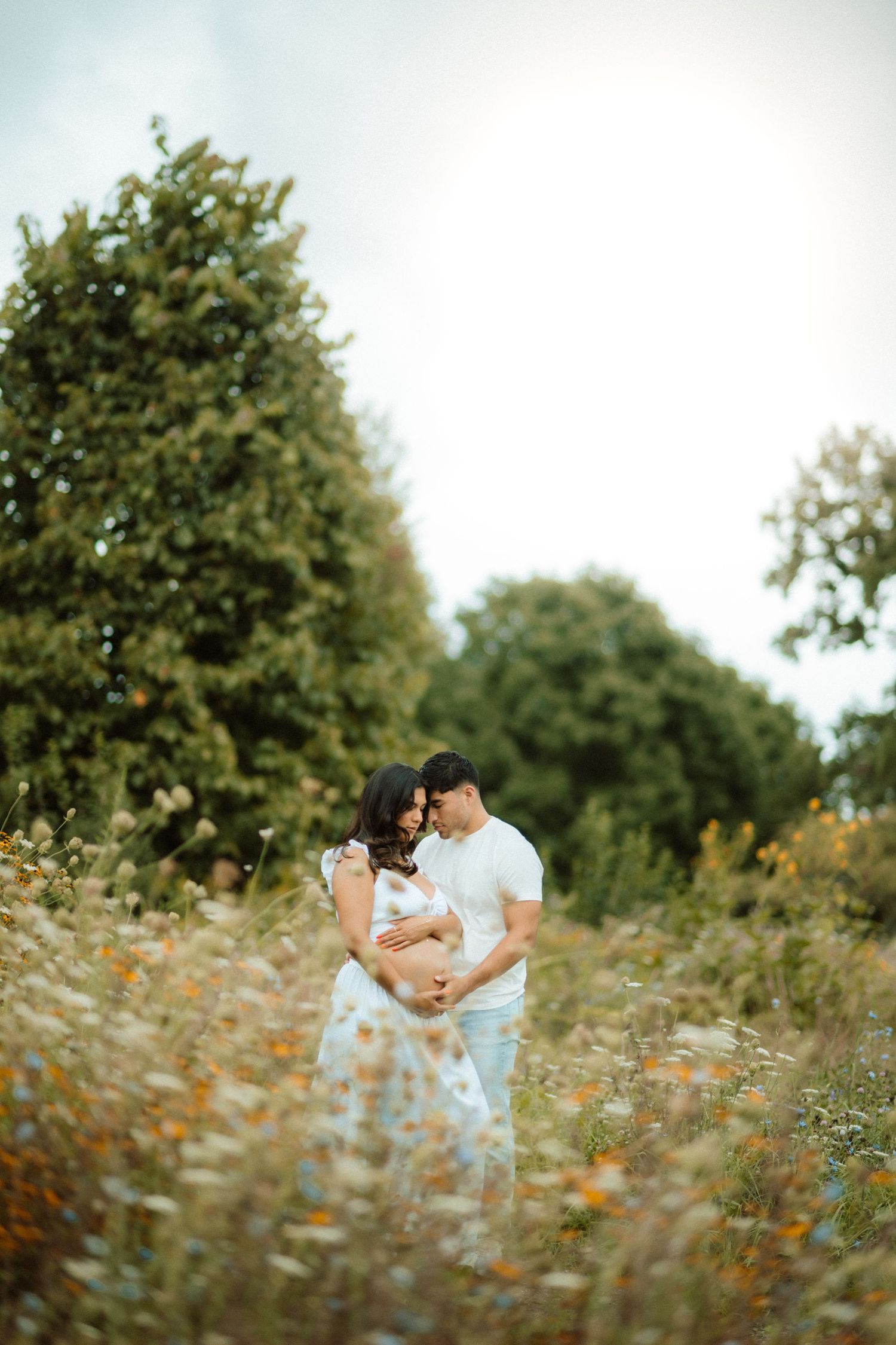 Romantic couple poses in a wildflower field during golden hour.