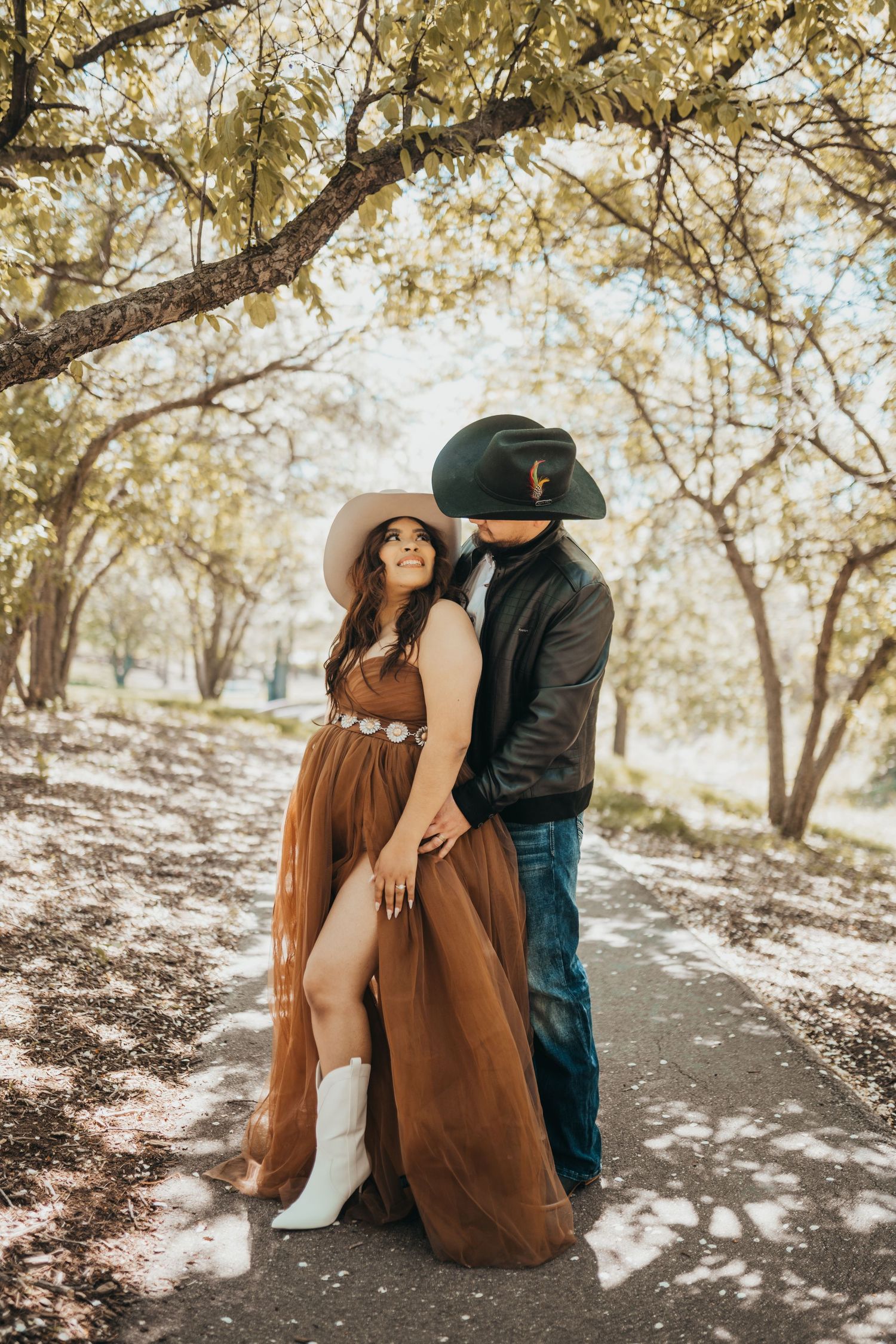 Couple sitting under dappled sunlight in an orchard setting.