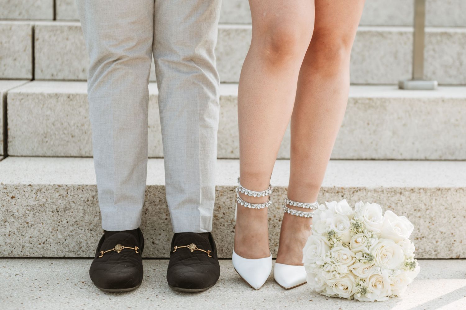 Detail shot of wedding shoes and bouquet resting on stone steps during ceremony.