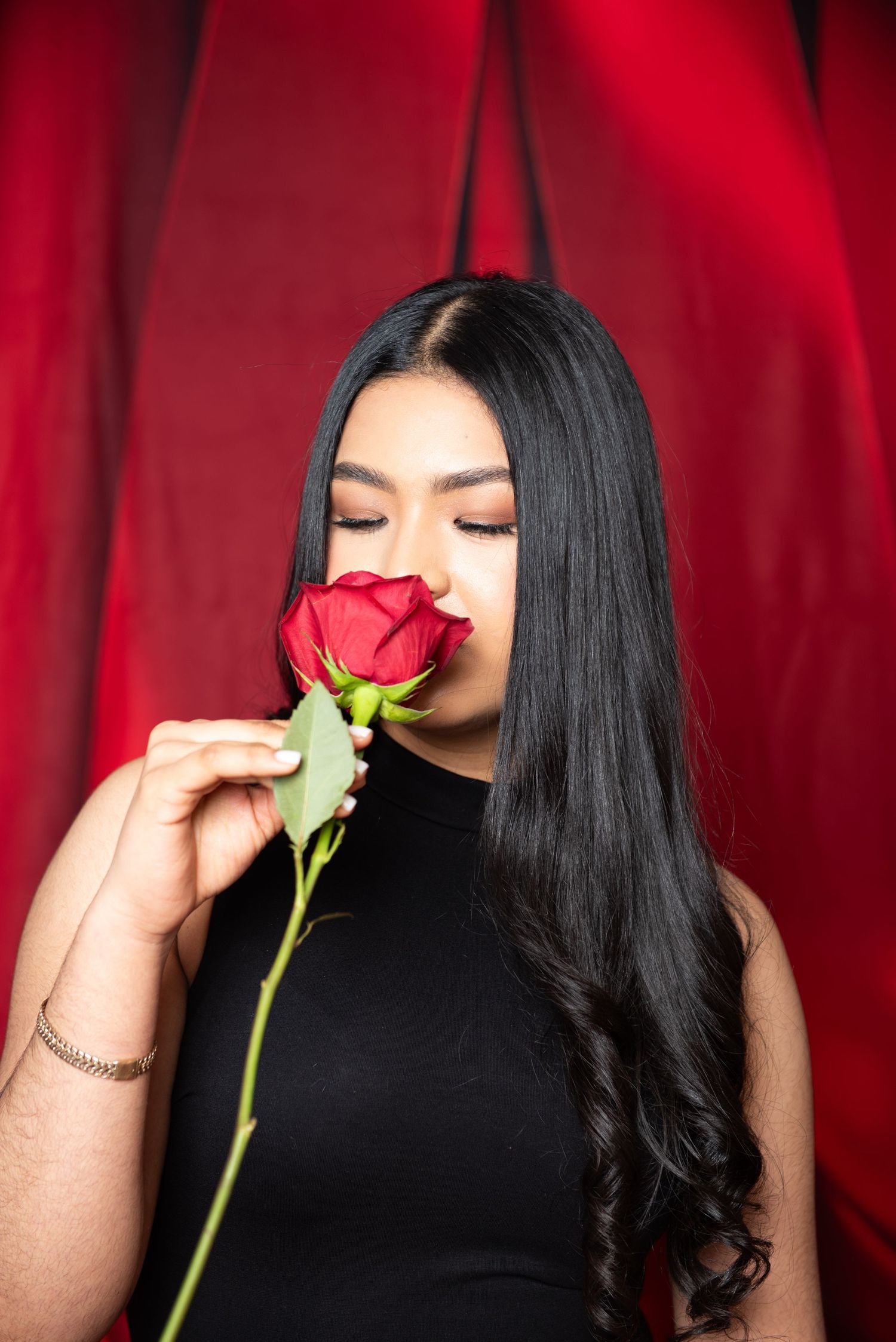 A series of close-up shots showing someone smelling a red rose against a crimson backdrop.