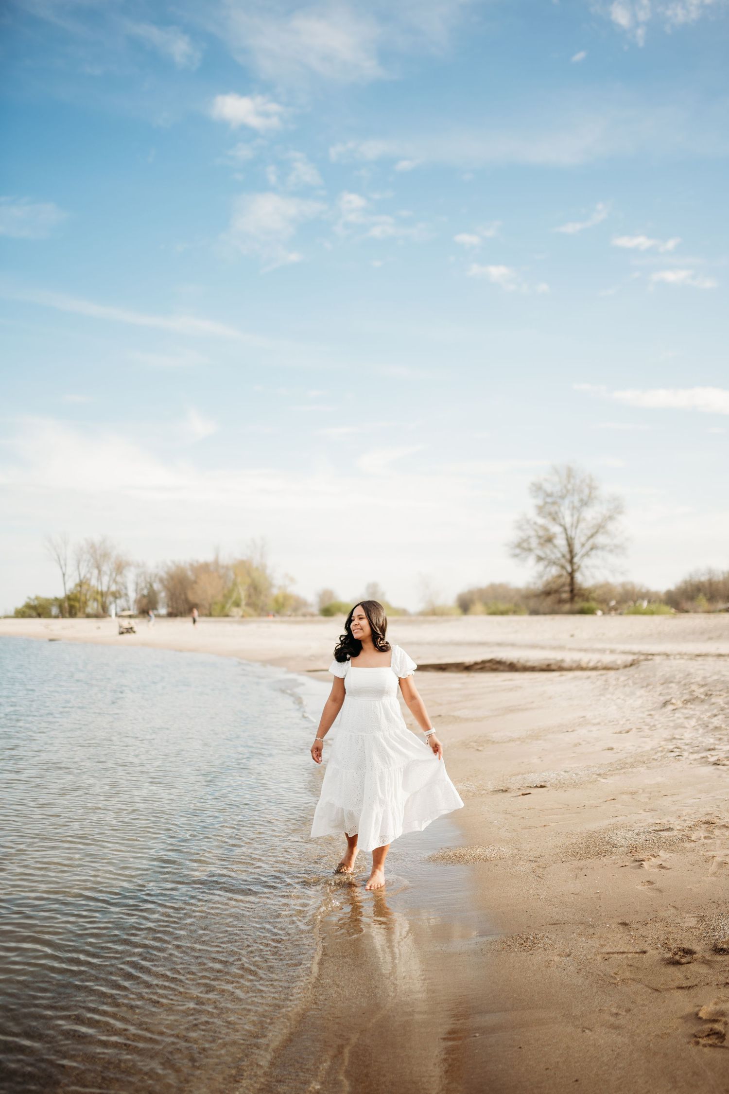 Couple walking along a serene beach shoreline at sunset.