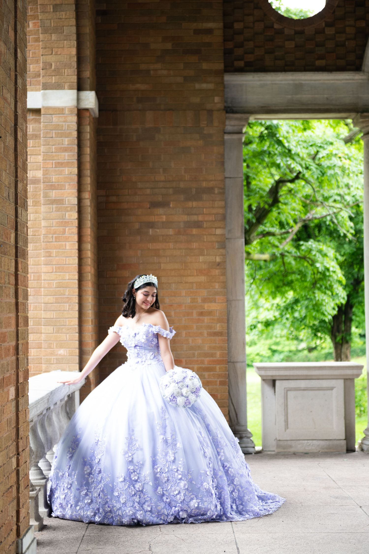 Elegant white ball gown photographed in brick colonnade with natural lighting.