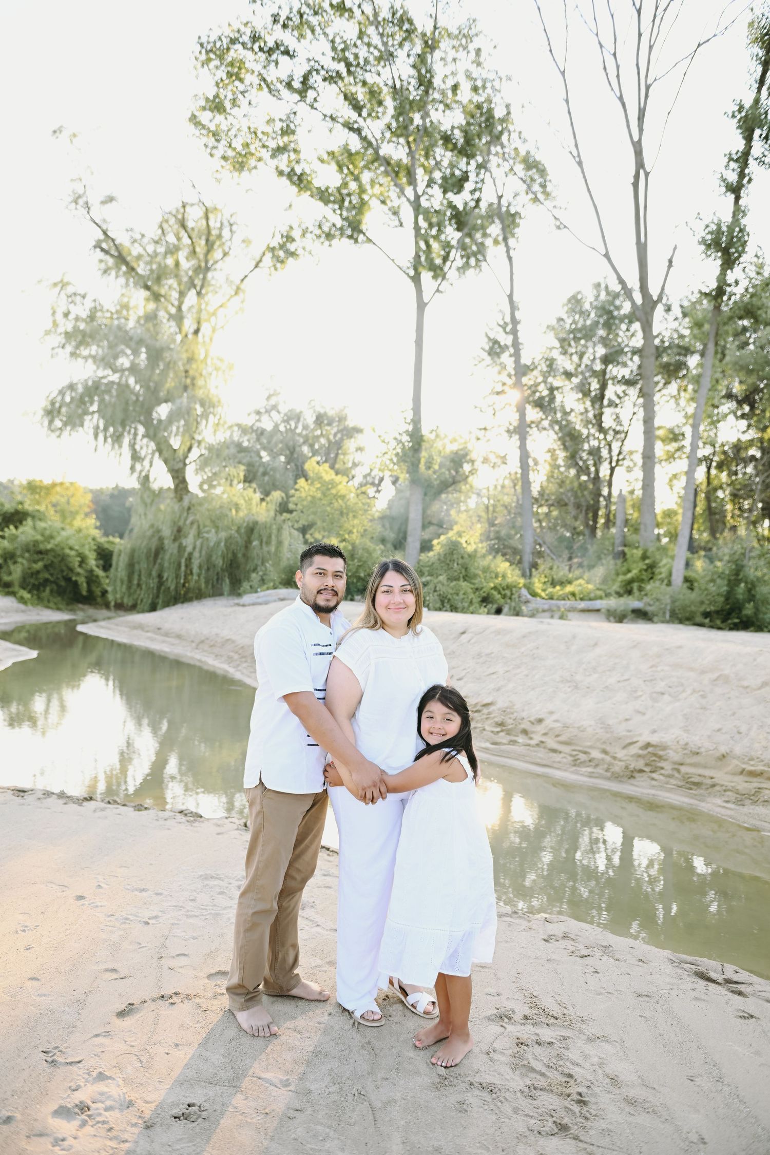 Couple poses together on a sandy riverbank during a sunset photo session.