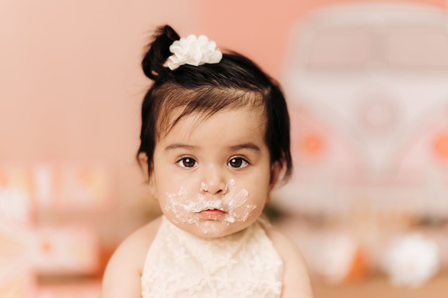 Baby portrait session with peachy pink background and white floral accents.