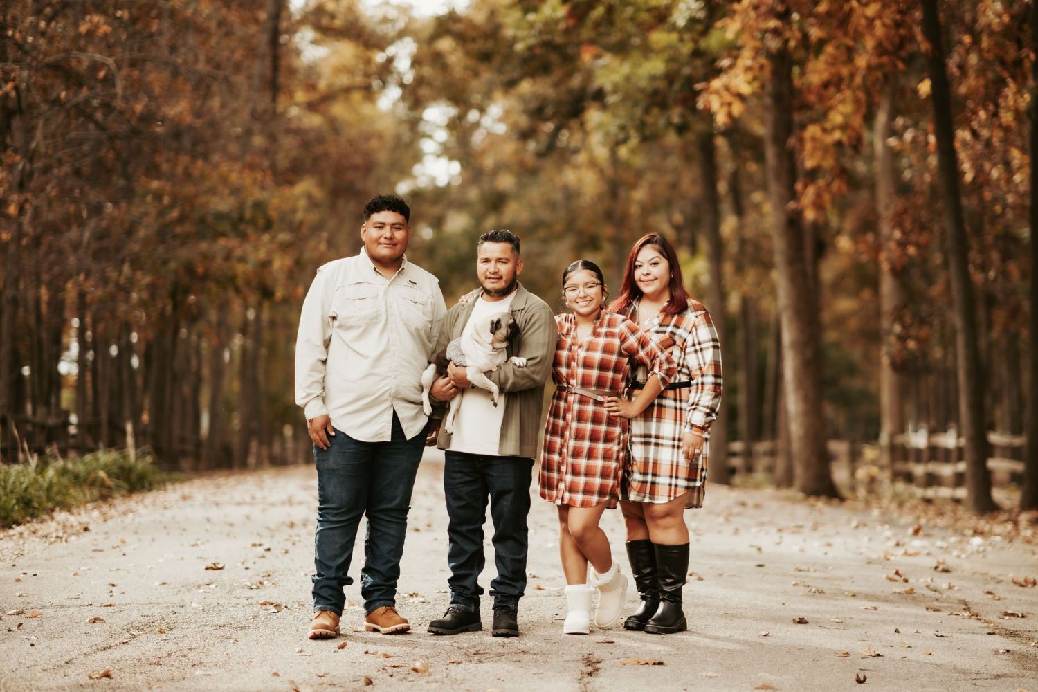 Family walking together on autumn path with fallen leaves in warm tones.