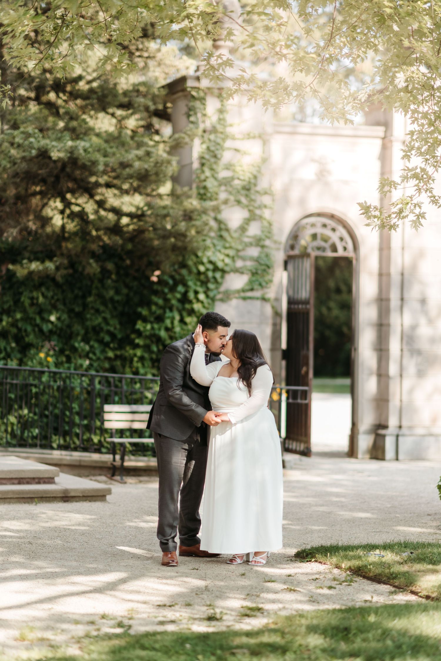 Wedding couple shares romantic moments in a garden setting with beautiful architecture.