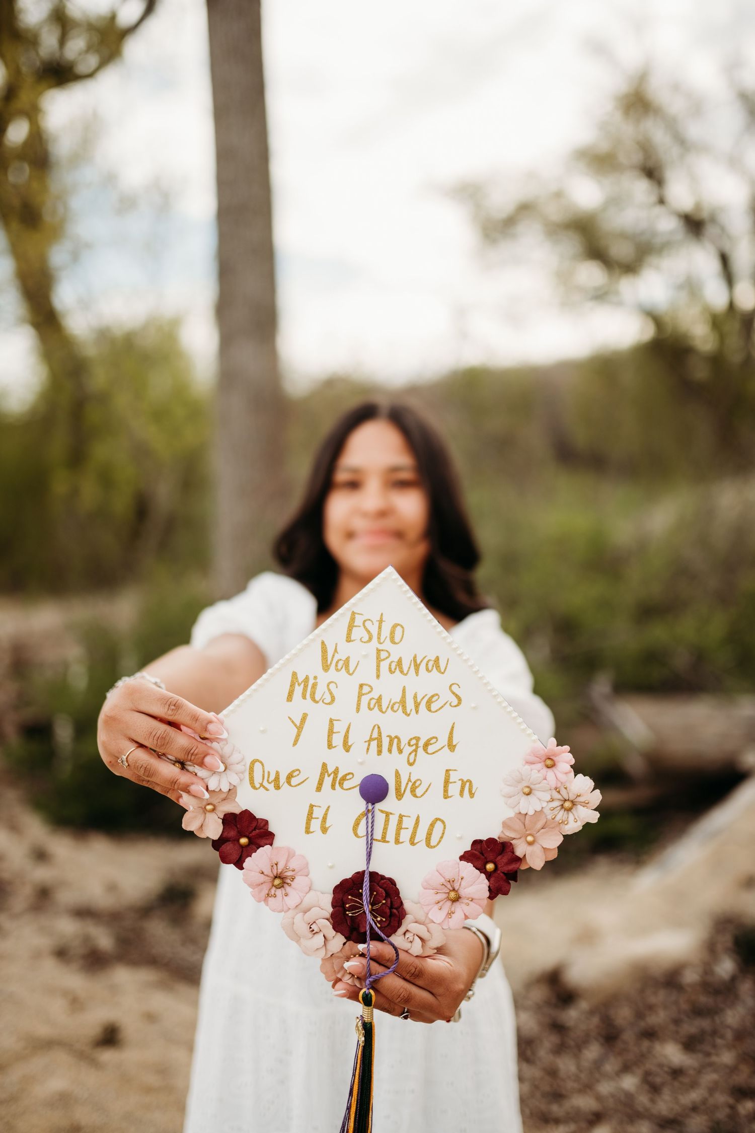 Decorated paper fans with gold text and pink flowers held against a natural outdoor background.