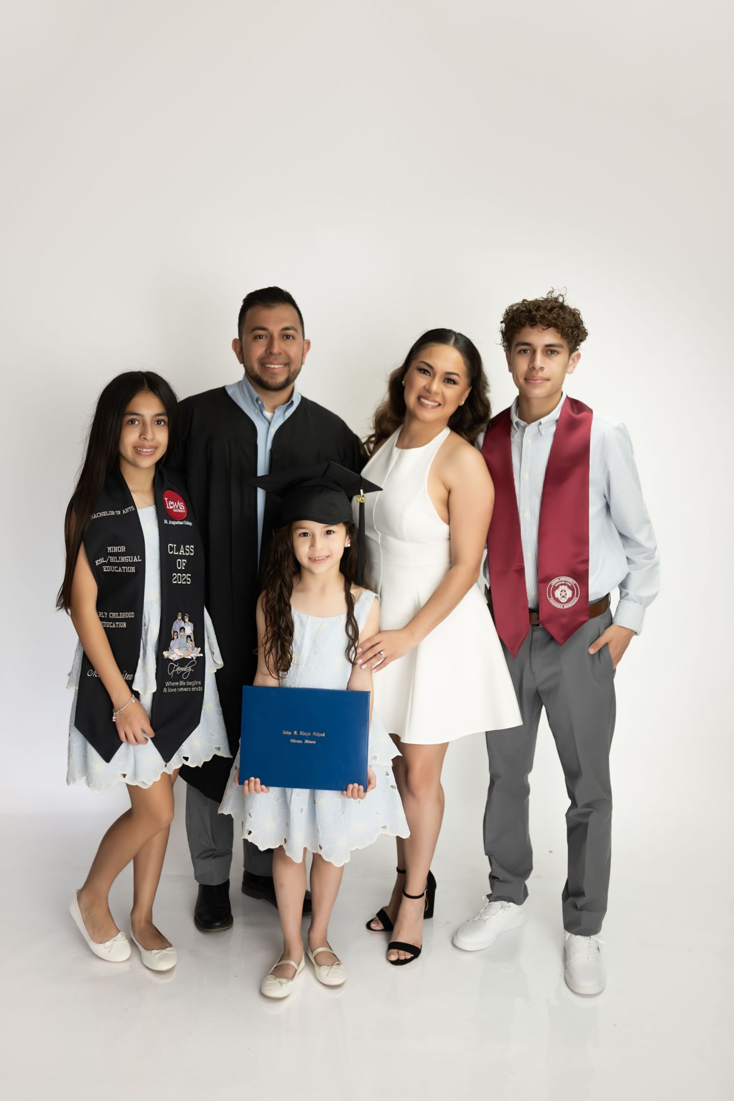 Group graduation photo with decorated sashes and formal attire against a white backdrop.
