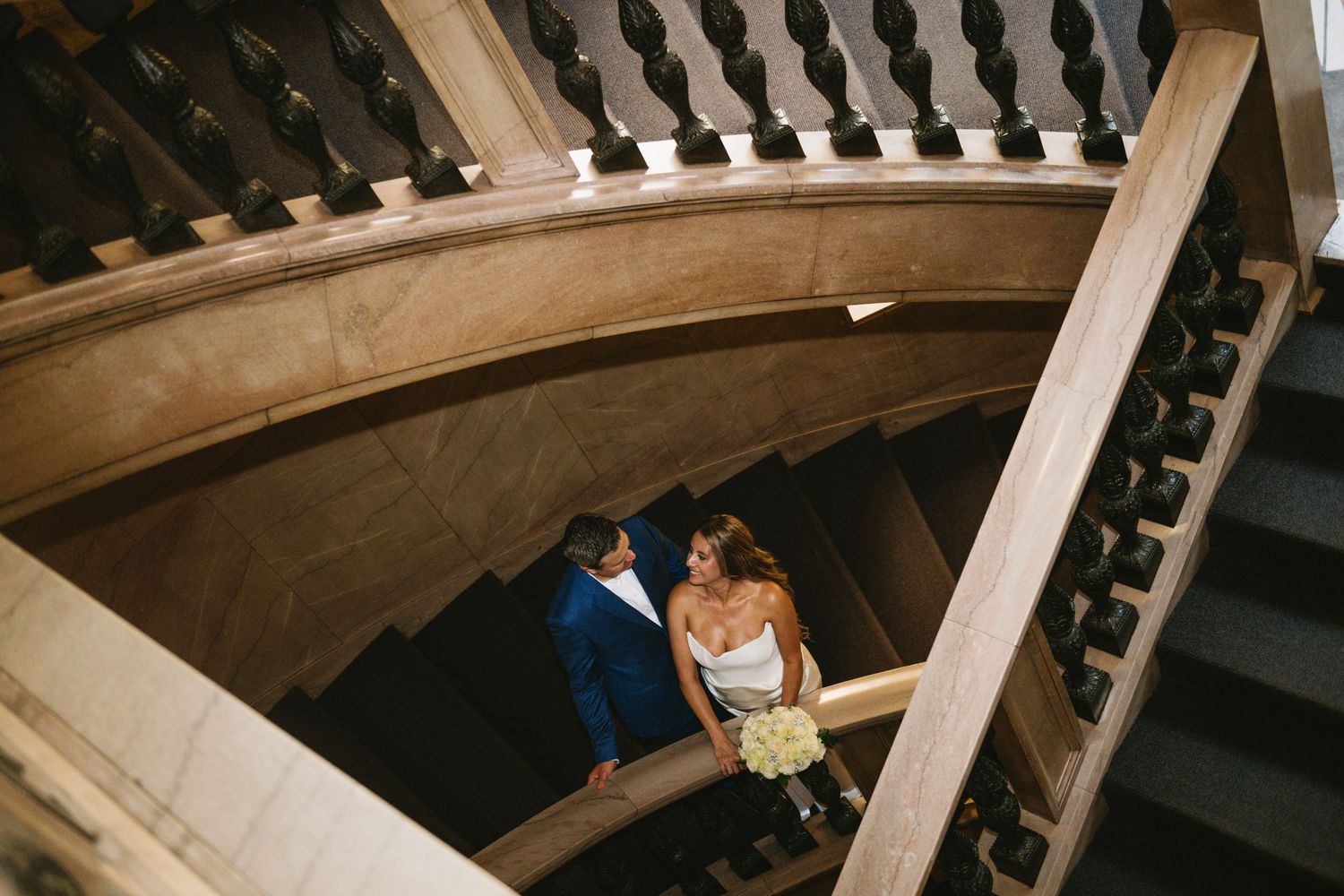 Elegant curved staircase with ornate black spindles in a grand indoor setting.