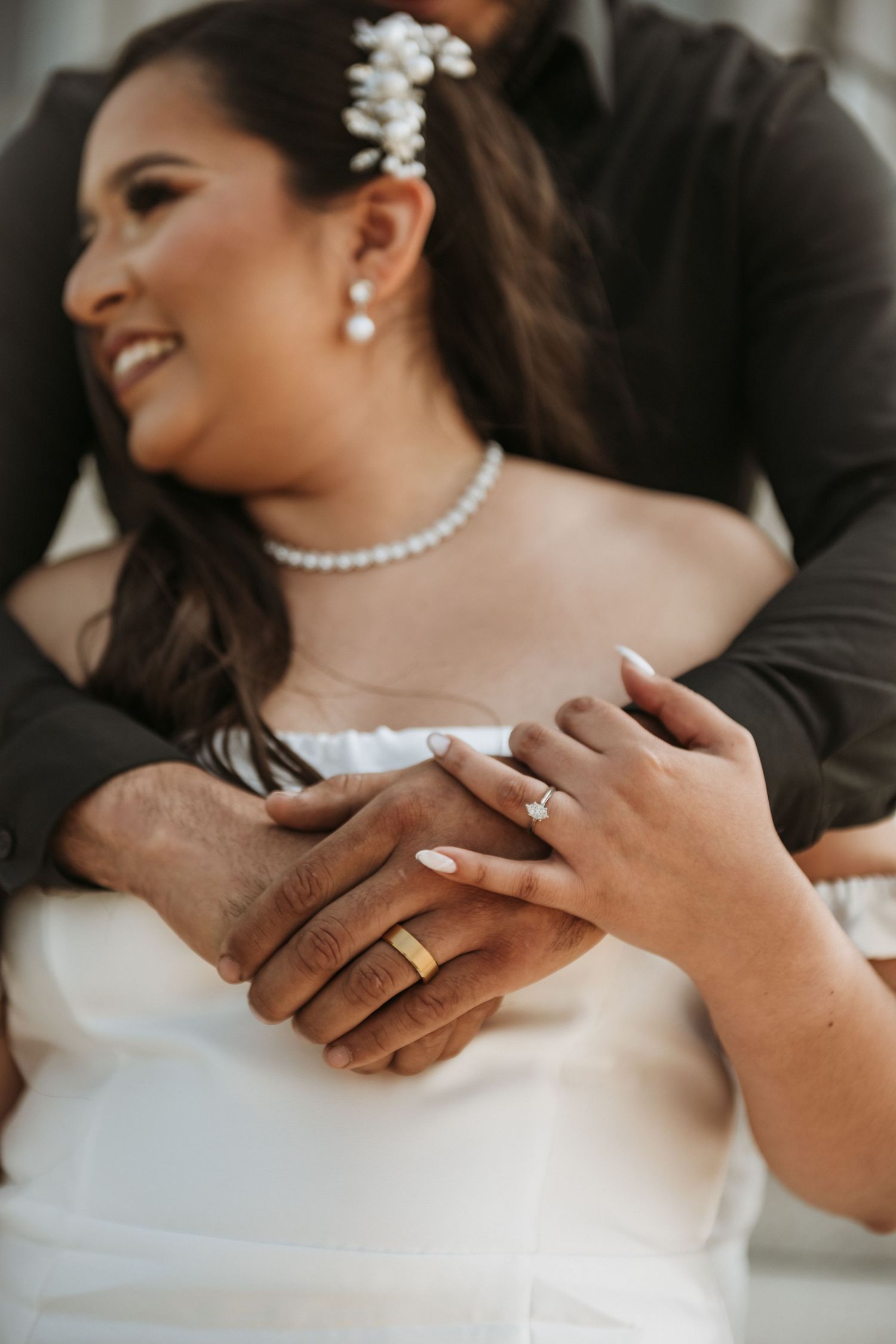 Close-up of wedding rings and hands showing intricate jewelry details and manicured nails.