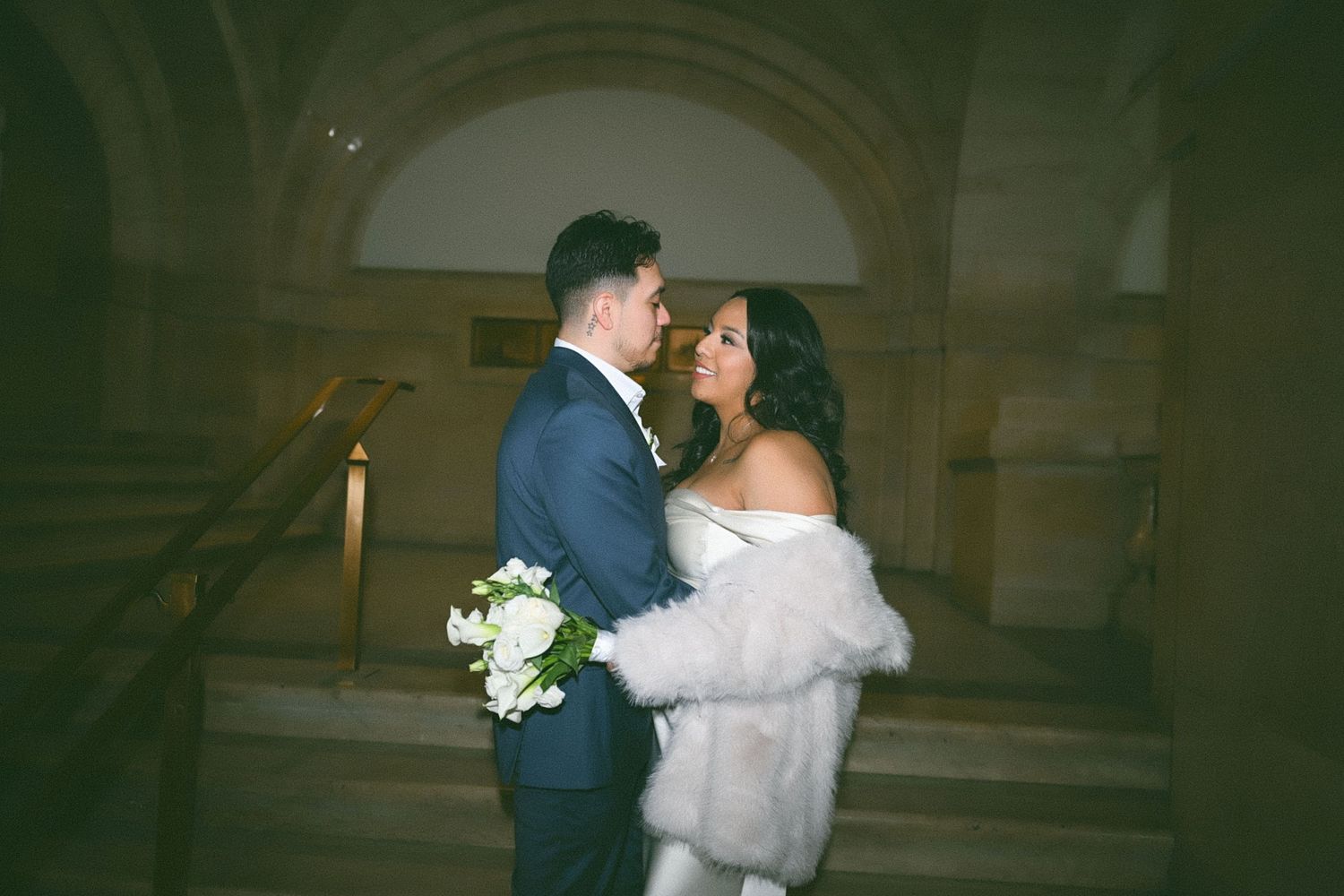 A couple shares an intimate dance moment in an elegant hallway.