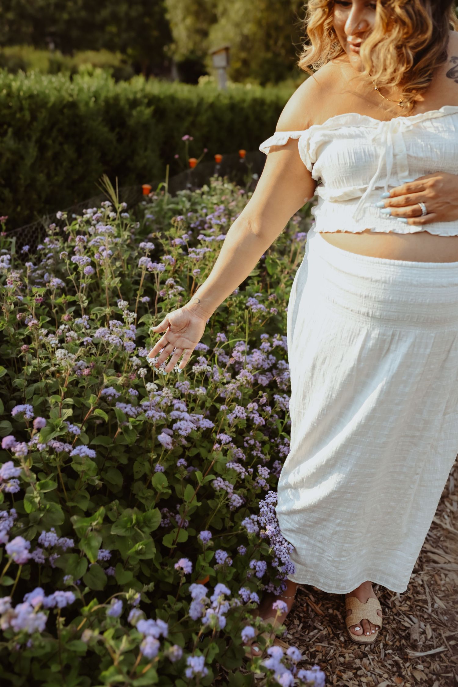 White dress flowing among purple wildflowers in a garden setting.